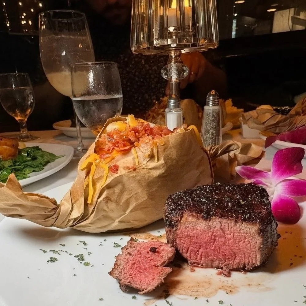 Steak and baked potato wrapped in paper with shredded cheese and toppings.