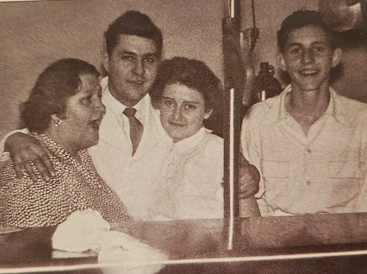 Four people gathered around a bar with a drink, smiling for the photo.
