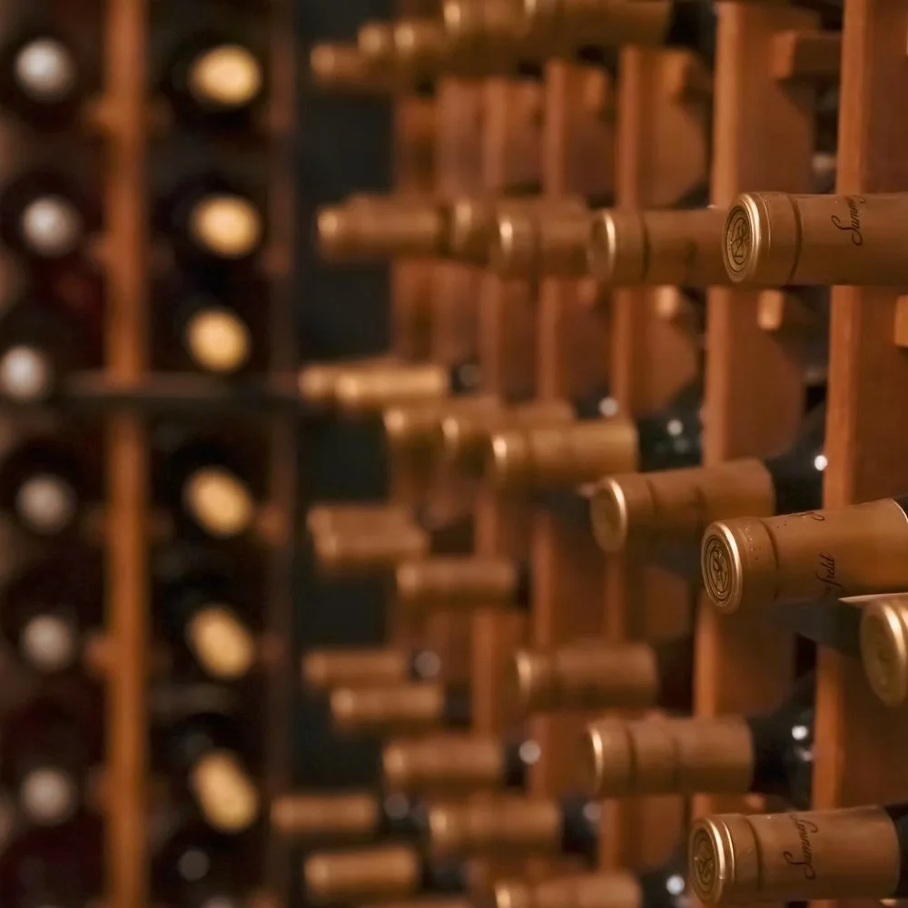 Rows of wine bottles stored horizontally on wooden racks in Sam's wine room.