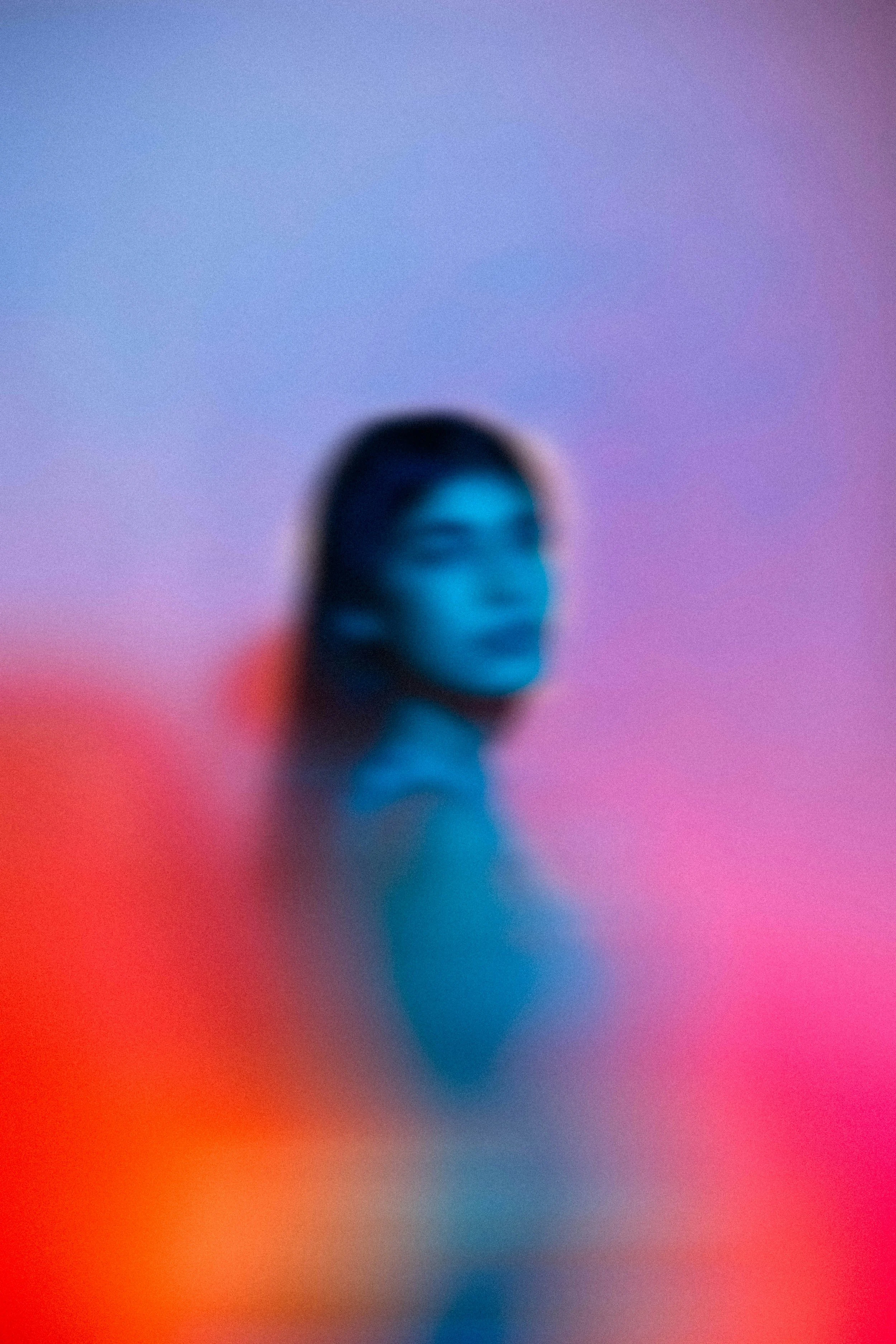 A blurred image of a human finger against a vibrant, colorful background with red, orange, pink, purple, blue, and violet hues.