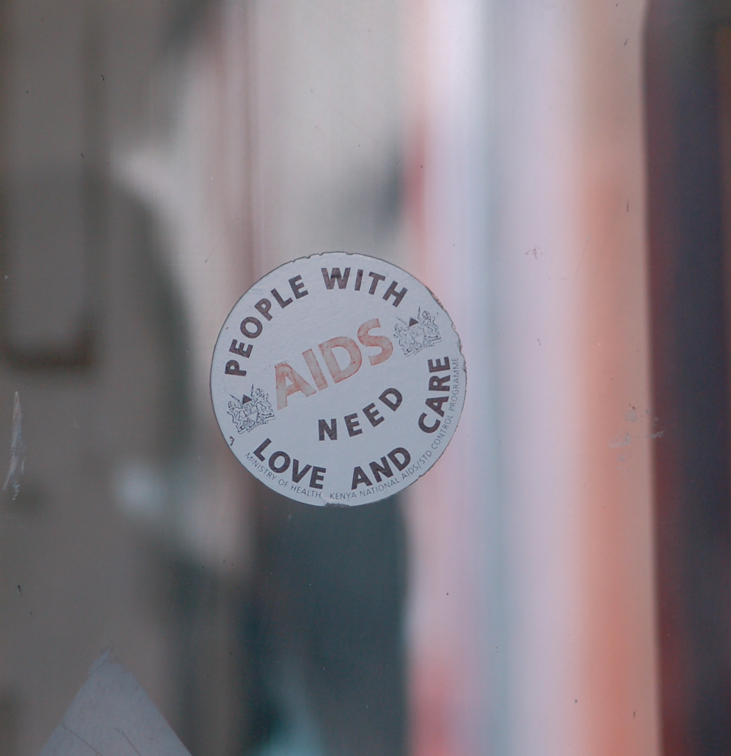 Image of sticker on window that says "people with AIDs need love and care"