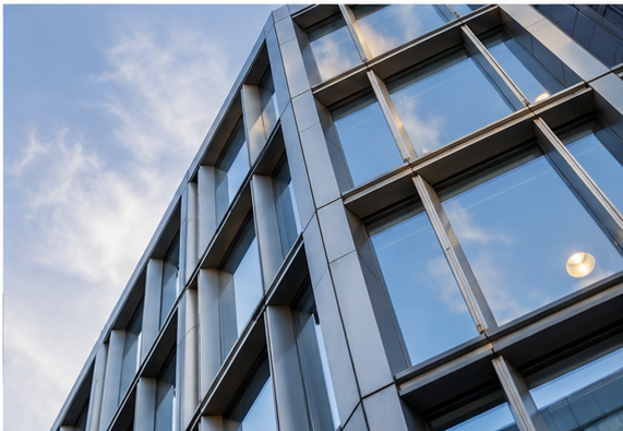 Close-up of a modern glass and metal office building with reflections of the sky on the windows.