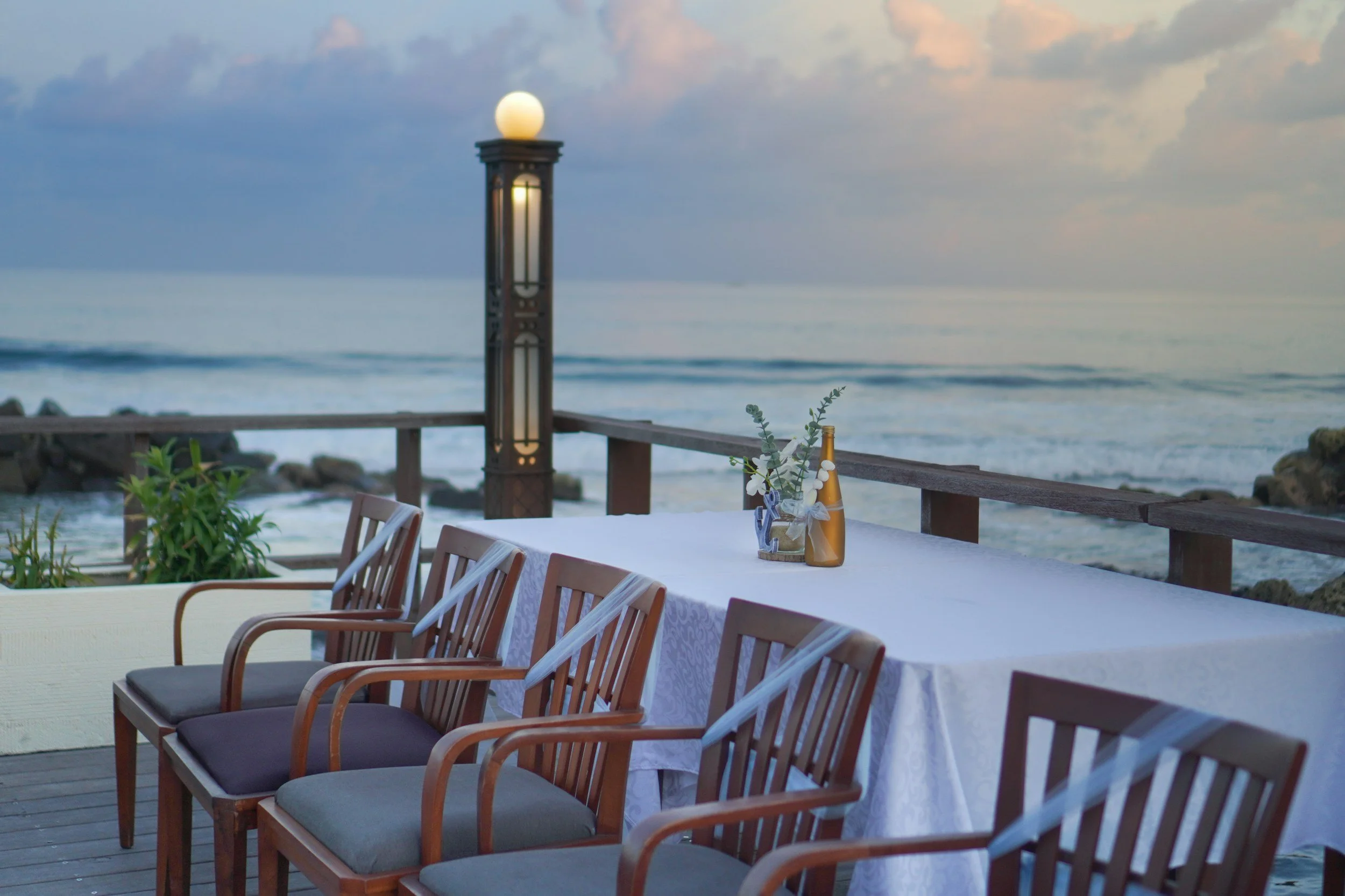 Long dinner table set on a seaside terrace at dusk, ready for an incentive trip gala dinner