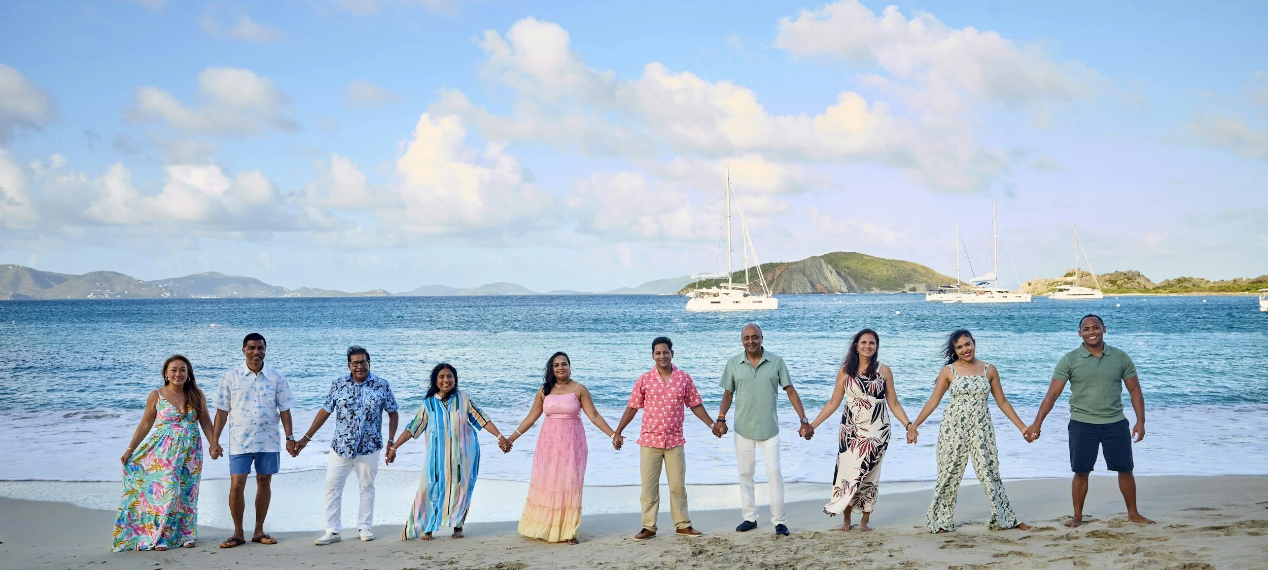 Extended family holding hands in a line on a Caribbean beach during a family reunion trip