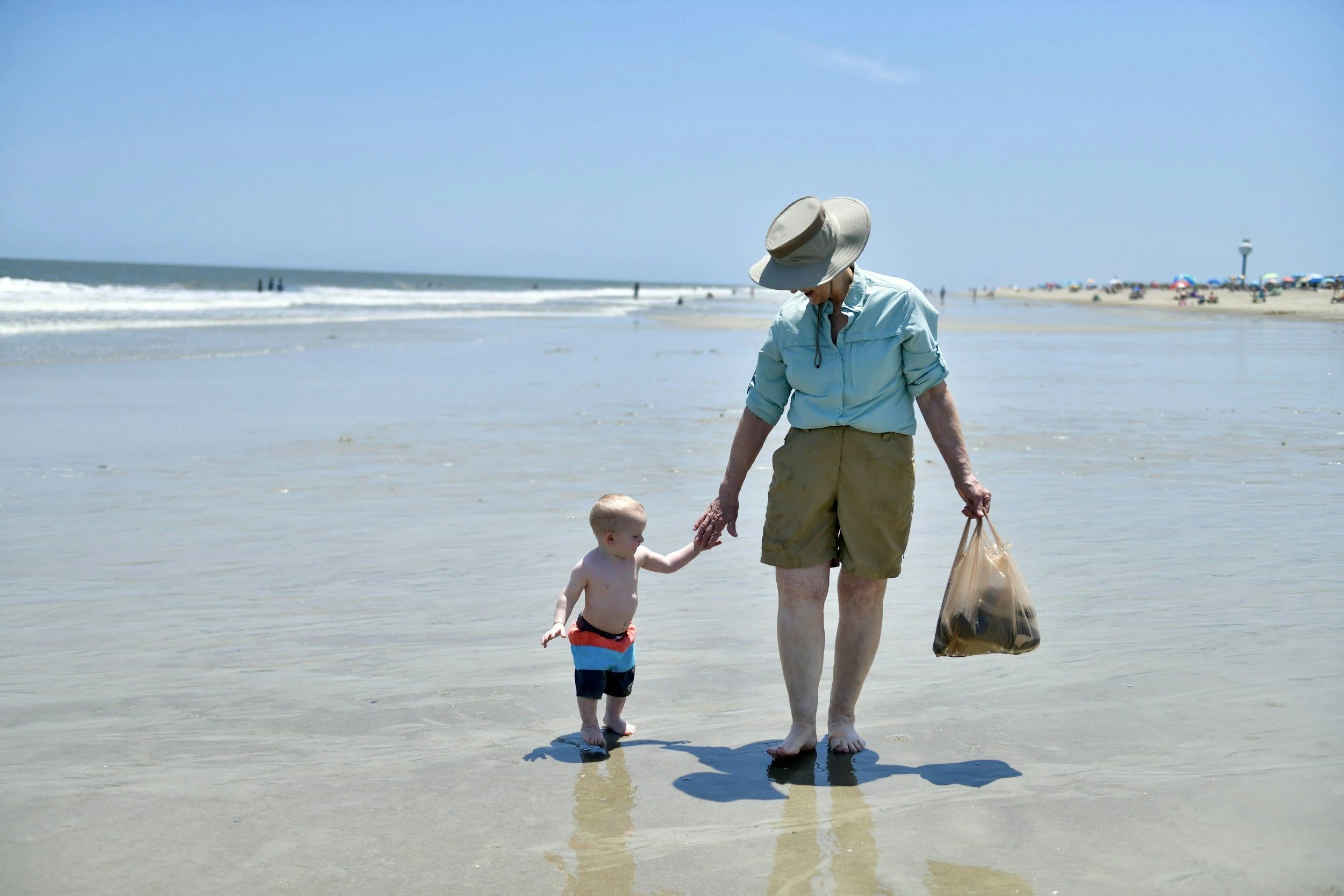 Grandmother walking hand in hand with her grandchild along the beach on a family vacation