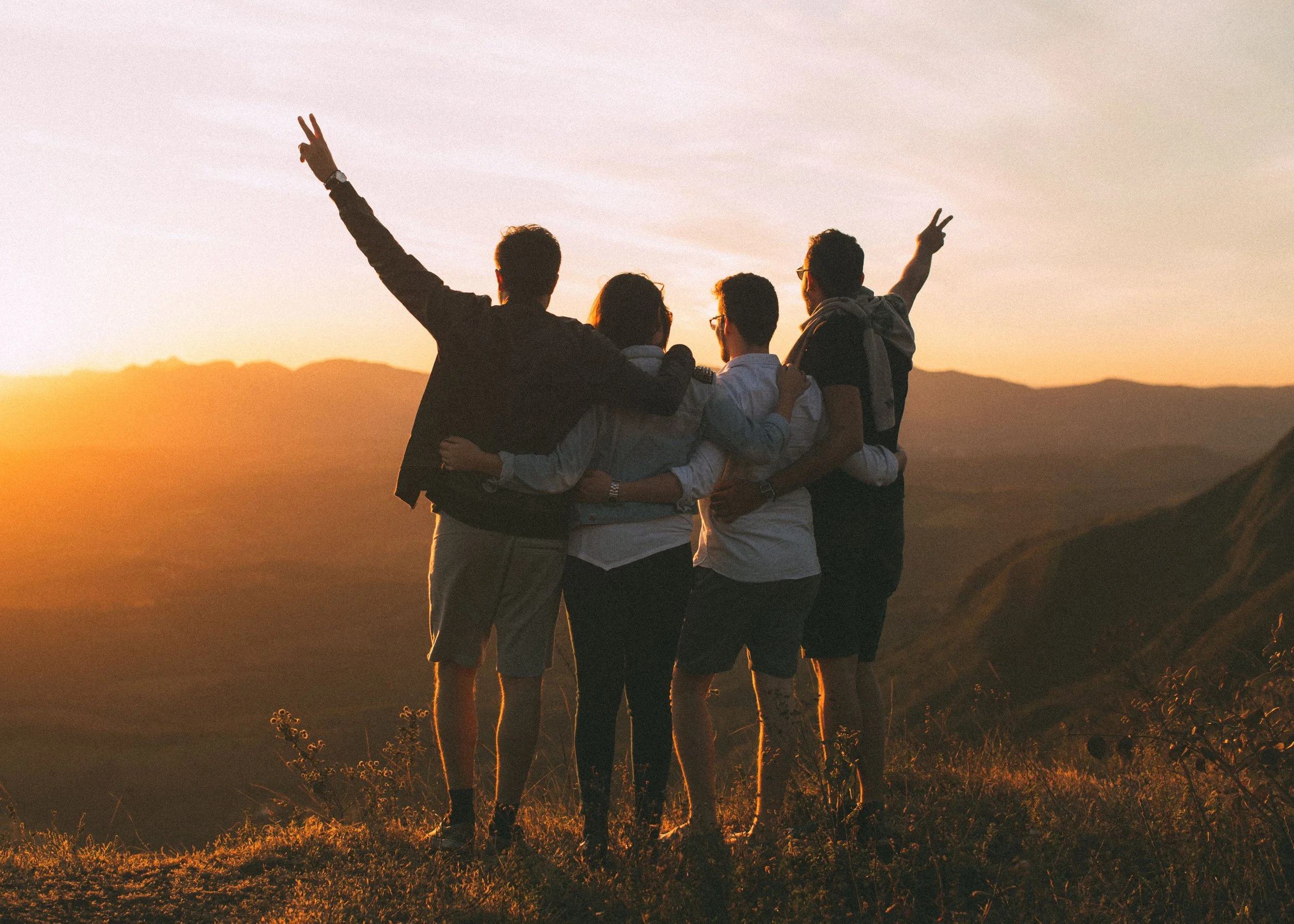 Group of friends enjoying a mountain sunset while on vacation.