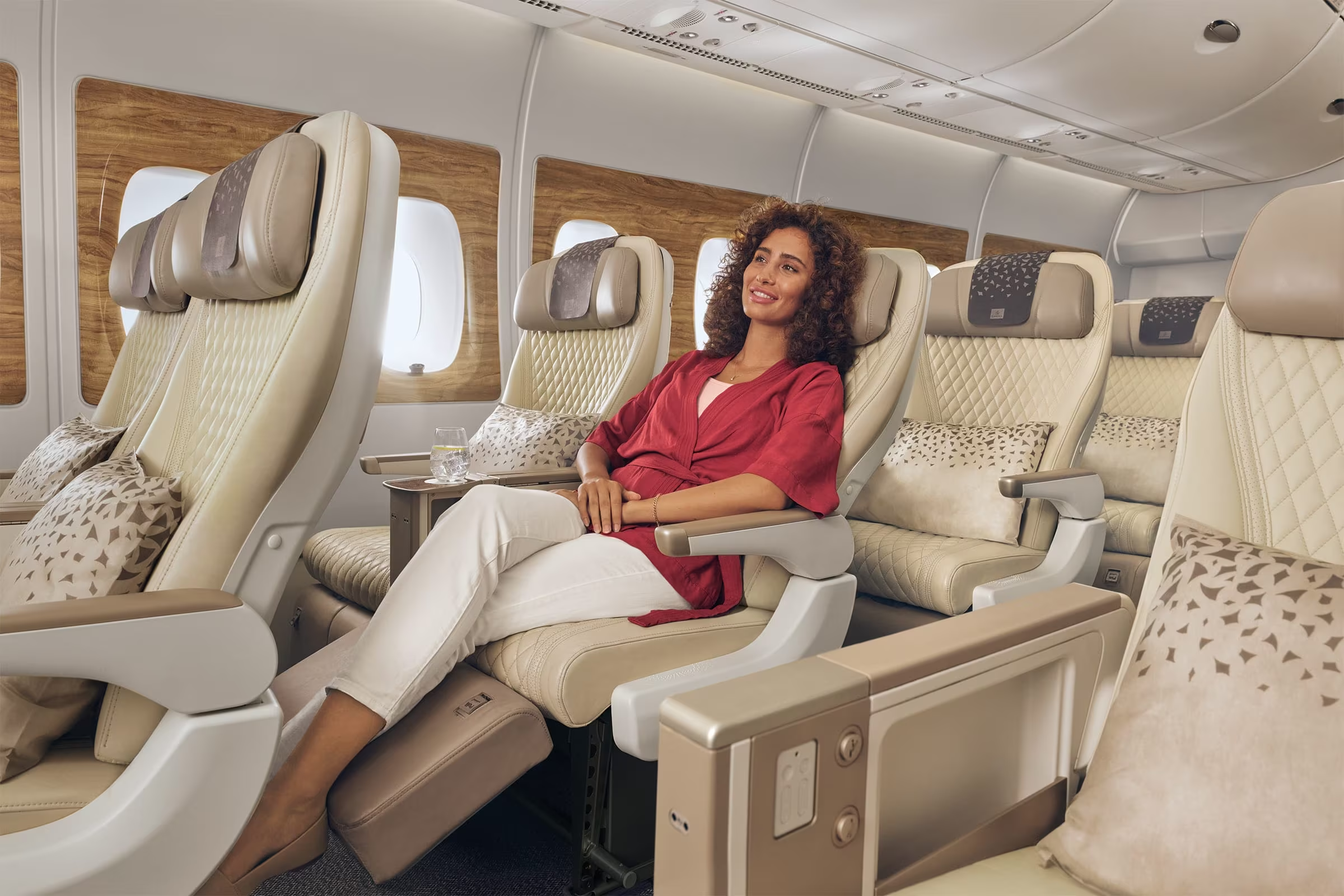 Happy woman smiling in a luxurious comfortable airline seat in a beautiful, clean airplane cabin.
