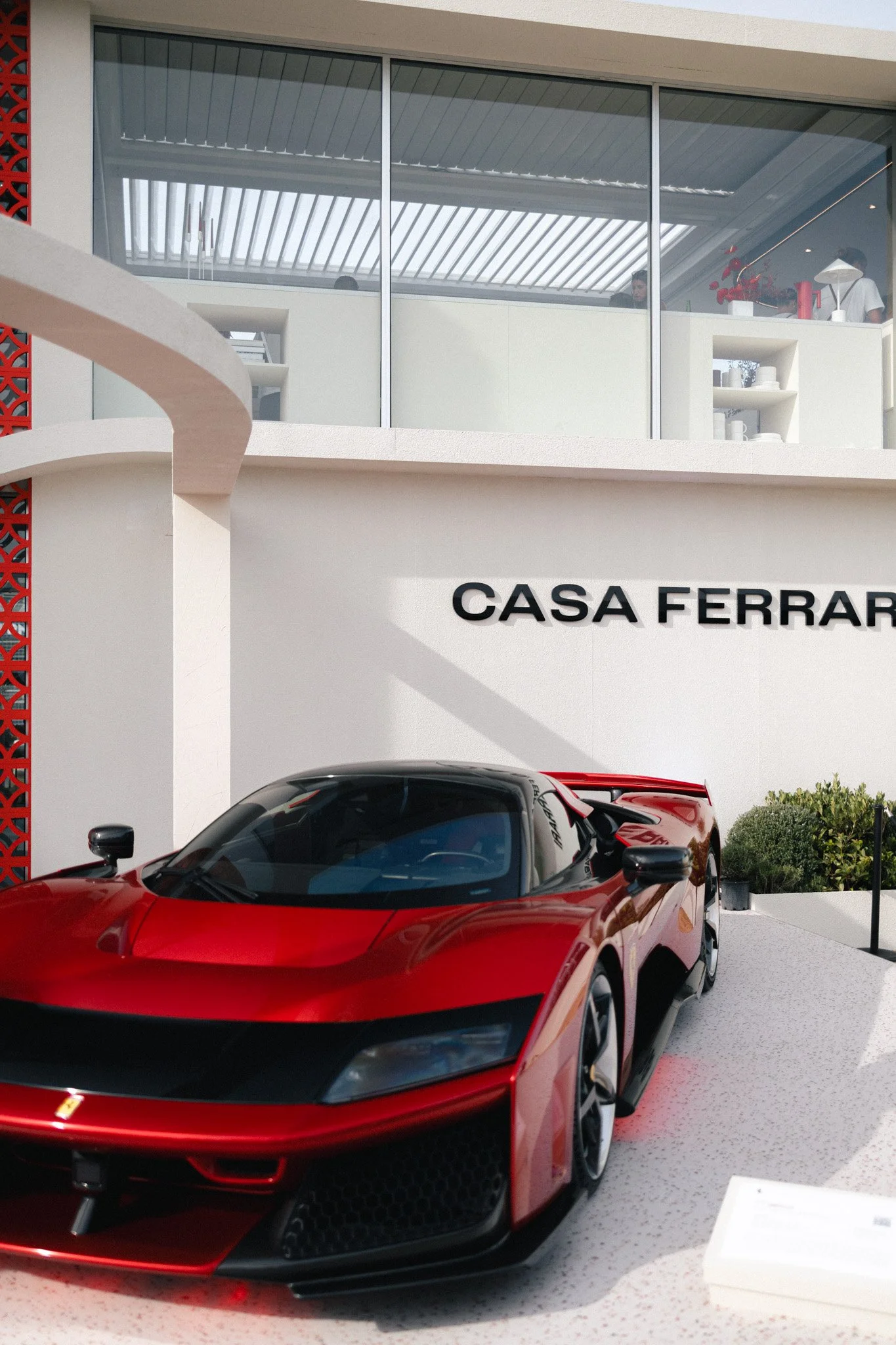 A red sports car parked outside a building with the sign 'Casa Ferrari' visible on the wall.