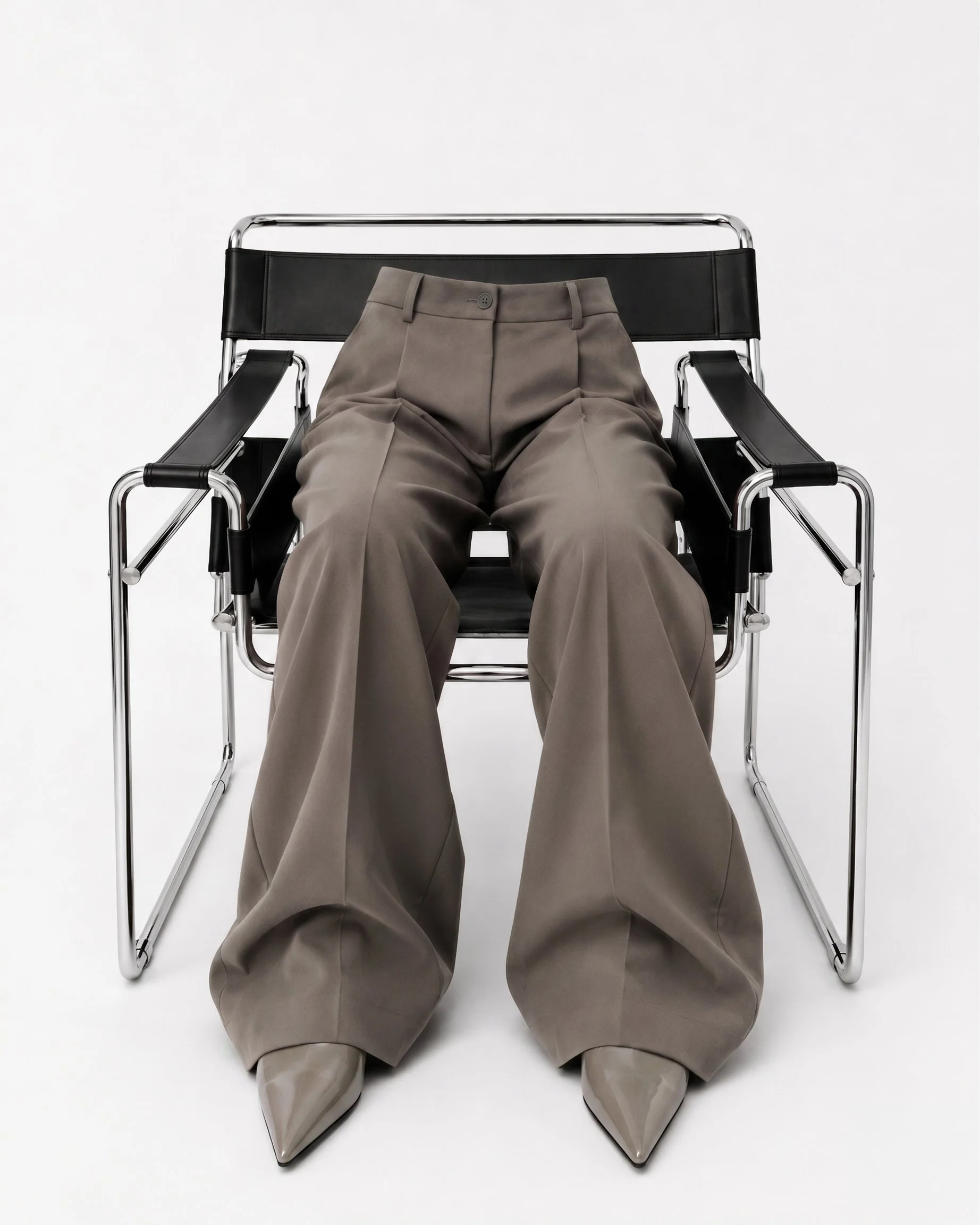 A metal and leather chair with gray trousers and gray high heels, set against a plain white background. Atantik, image consulting, image consultant, style, fashion, creative, moodboard, editorial style