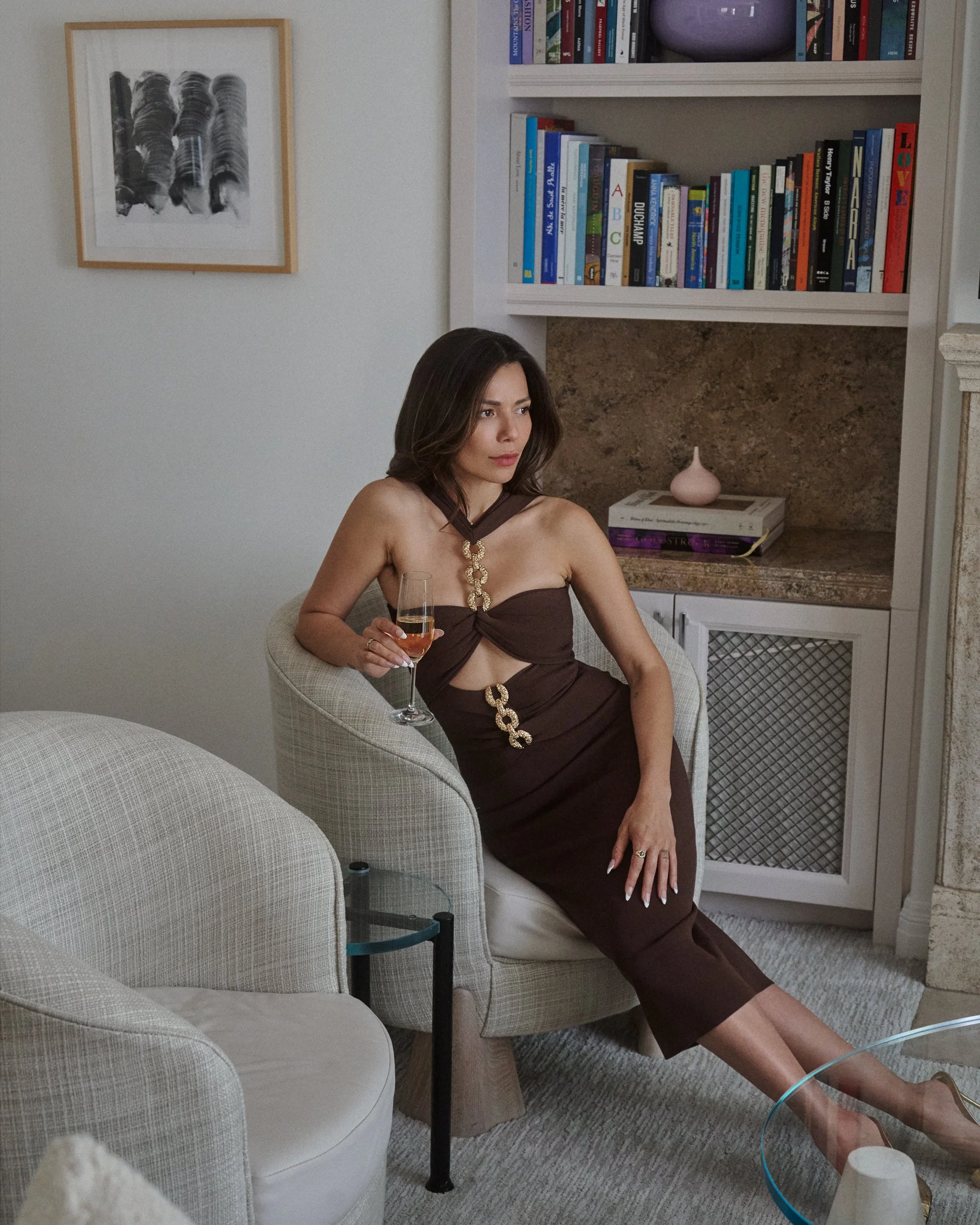 Veronica Wilder in a brown & gold Cult Gaia dress with a glass of wine in a book-lined room, the Garden Suite at the Maybourne Hotel in Beverly Hills, film photograph