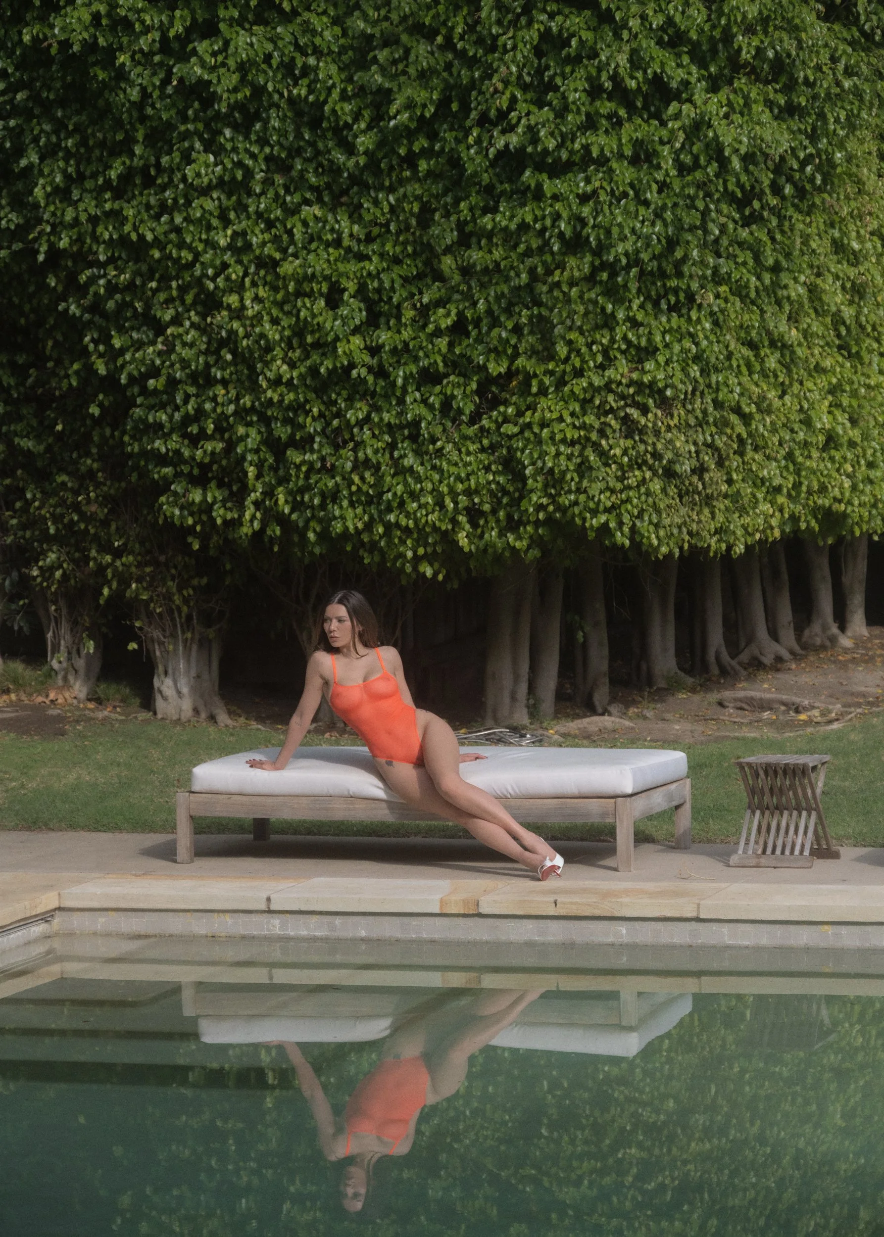 Veronica Wilder on a daybed beside a garden pool, Los Angeles, film photograph. 