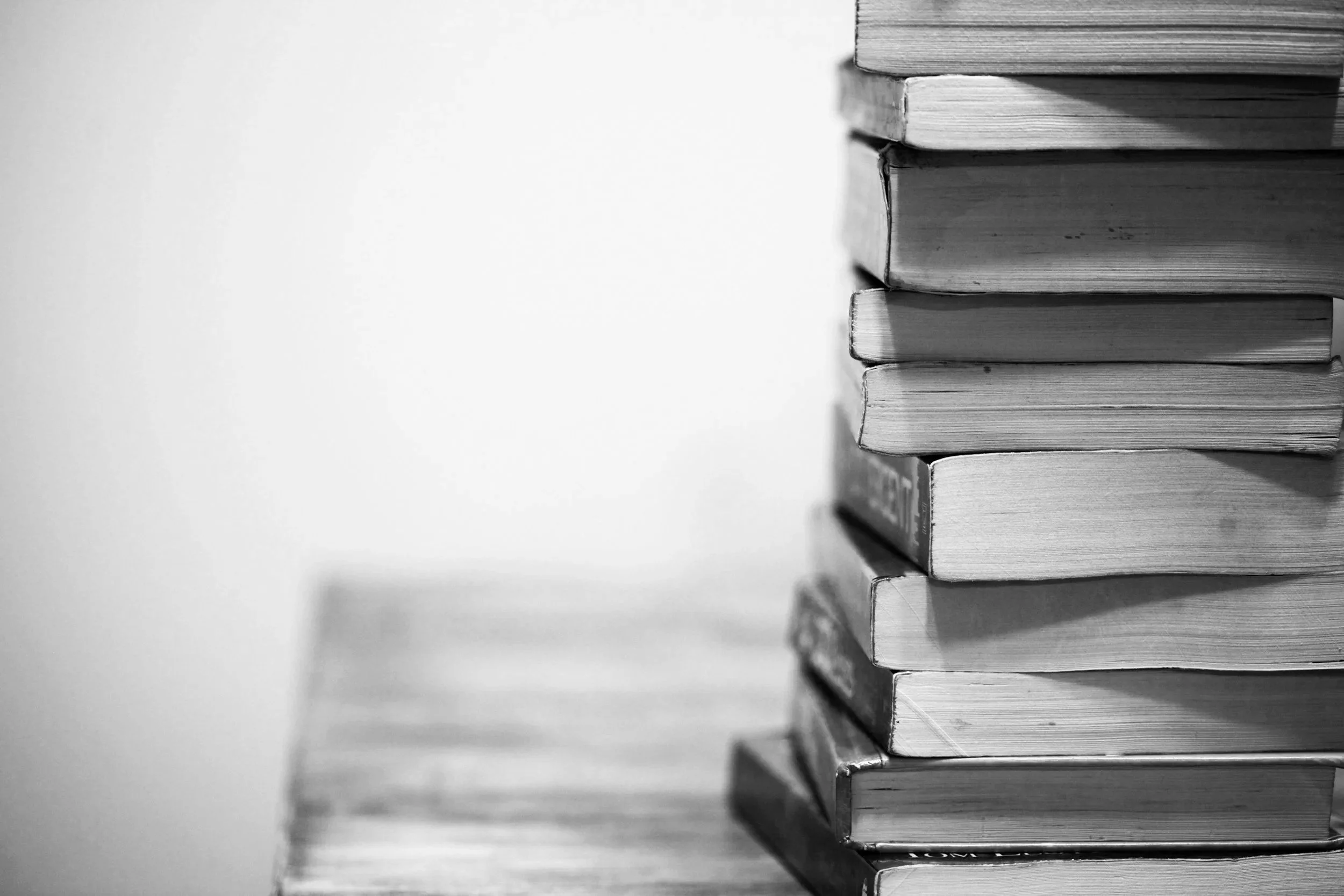 Close-up of a stack of books in black and white, with the right side of the books visible against a plain white background.