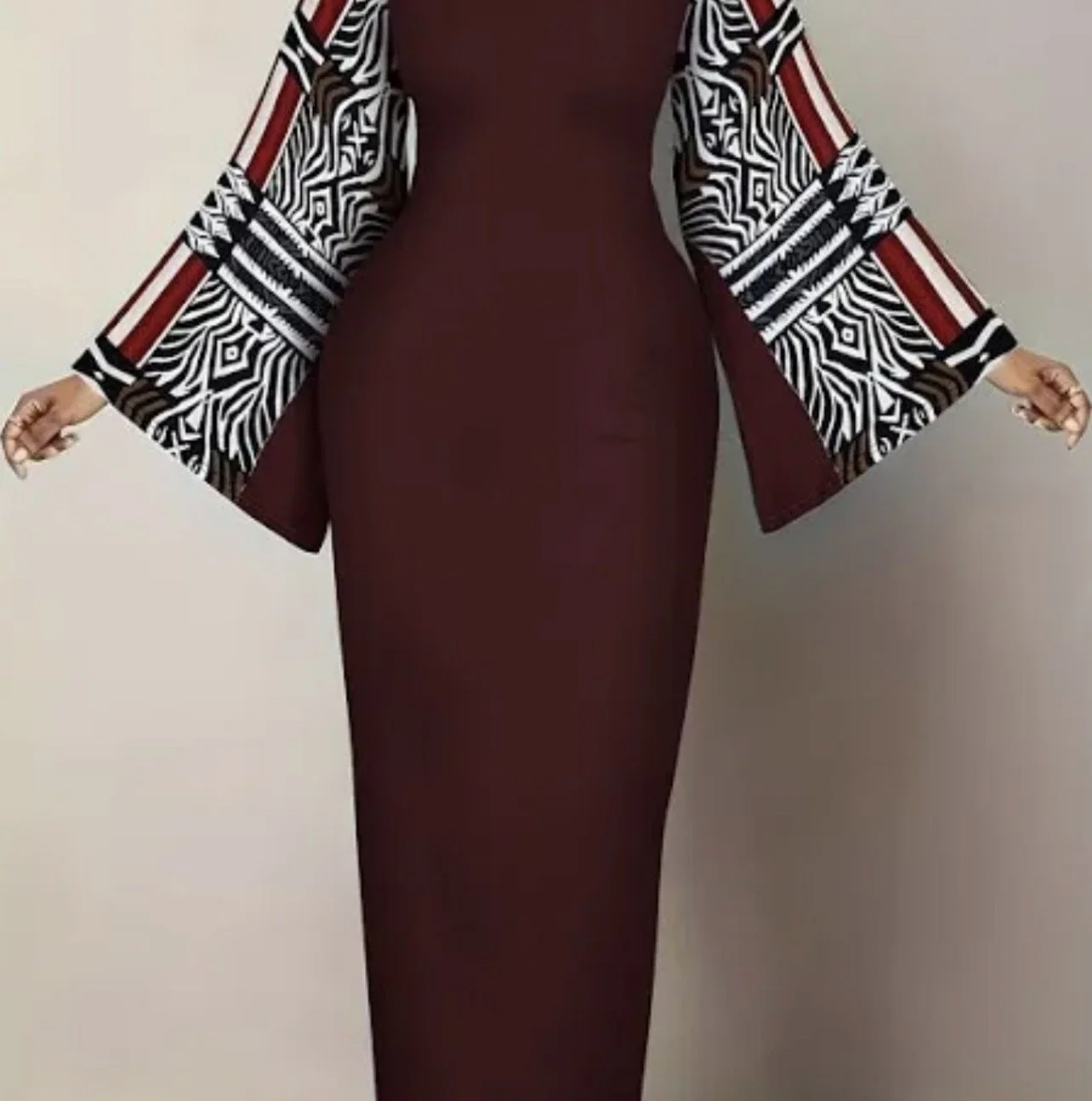 A person wearing a maroon dress and a black, white, and red patterned jacket, with arms extended outward, against a plain background. cheekychk