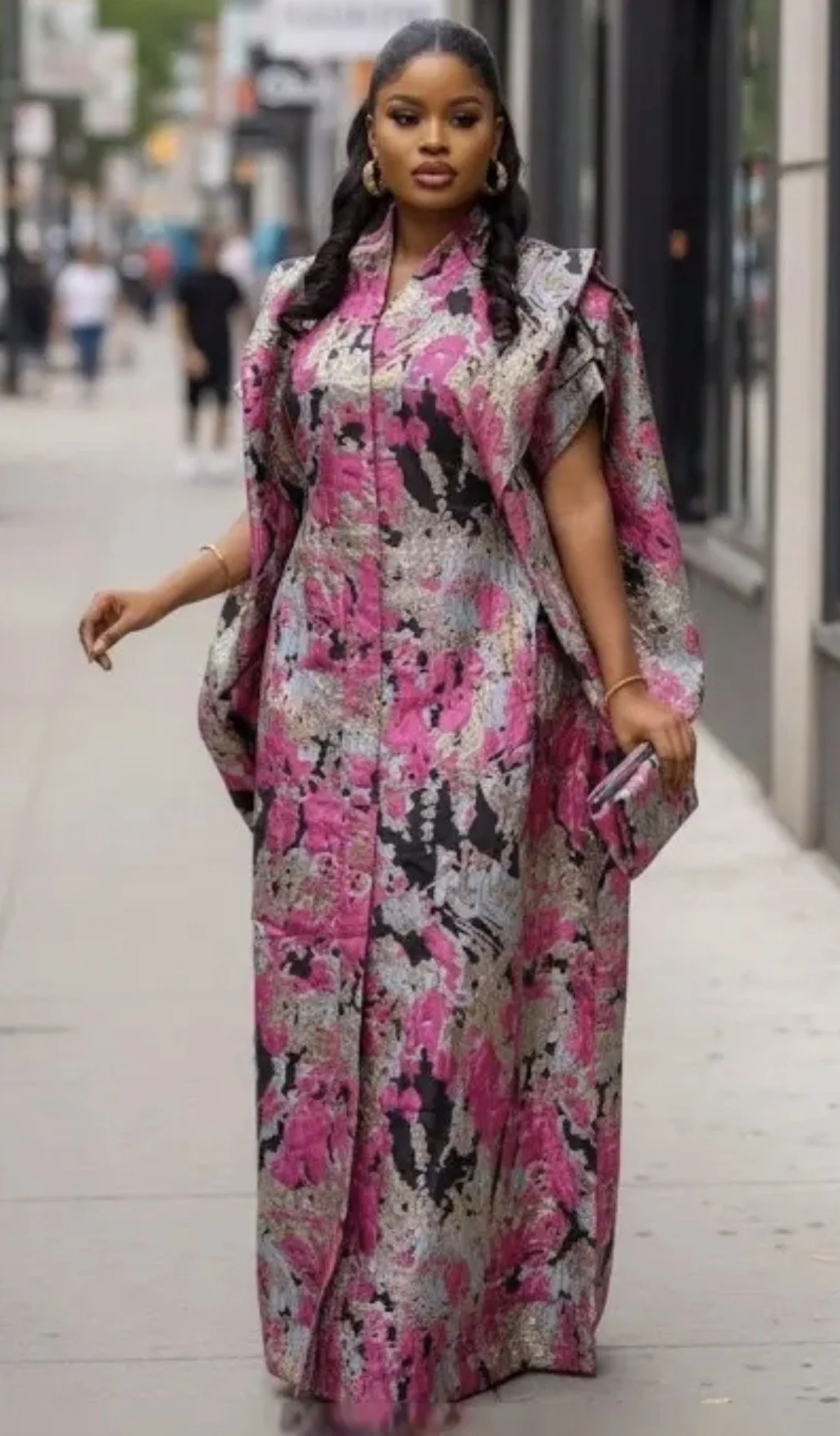 Woman wearing a pink, black, and white patterned dress walking on a city sidewalk. cheekychk