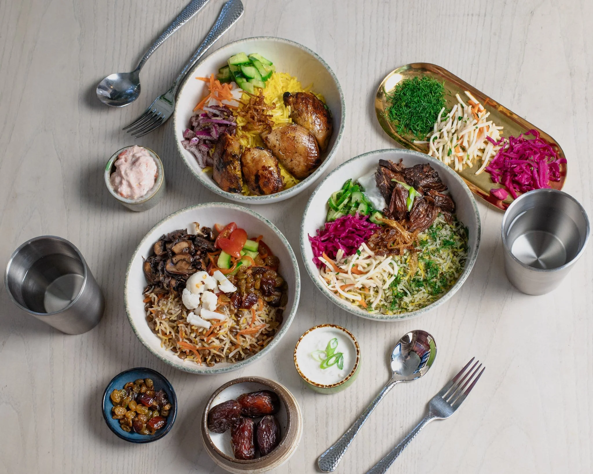 Baloot saffron chicken, braised short rib, and adas polo bowls with Persian pickles