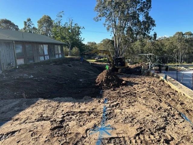 Construction site with dirt and blue marking lines, with an excavator