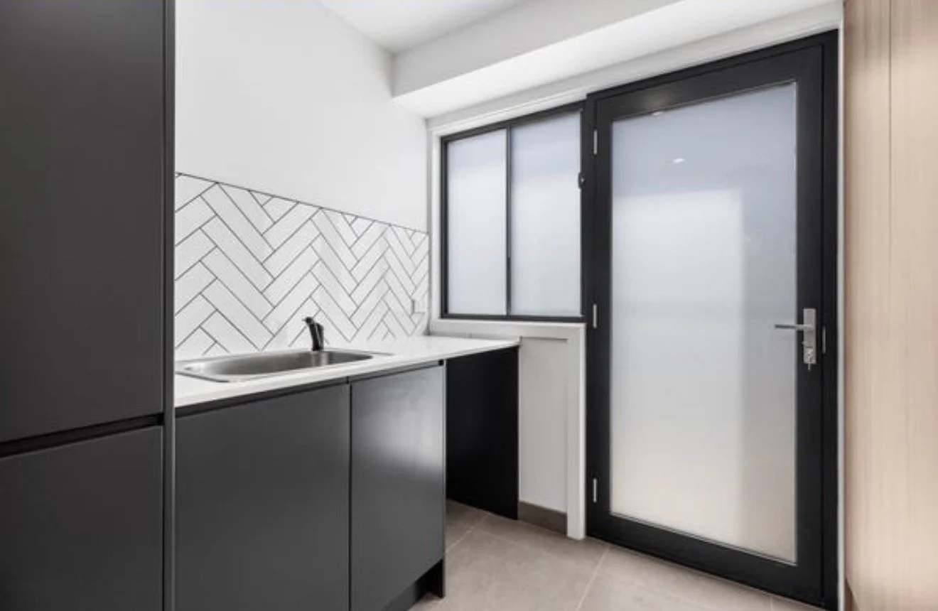 Modern kitchen corner with black cabinets, a stainless steel sink, a black-framed window, and a black sliding glass door.