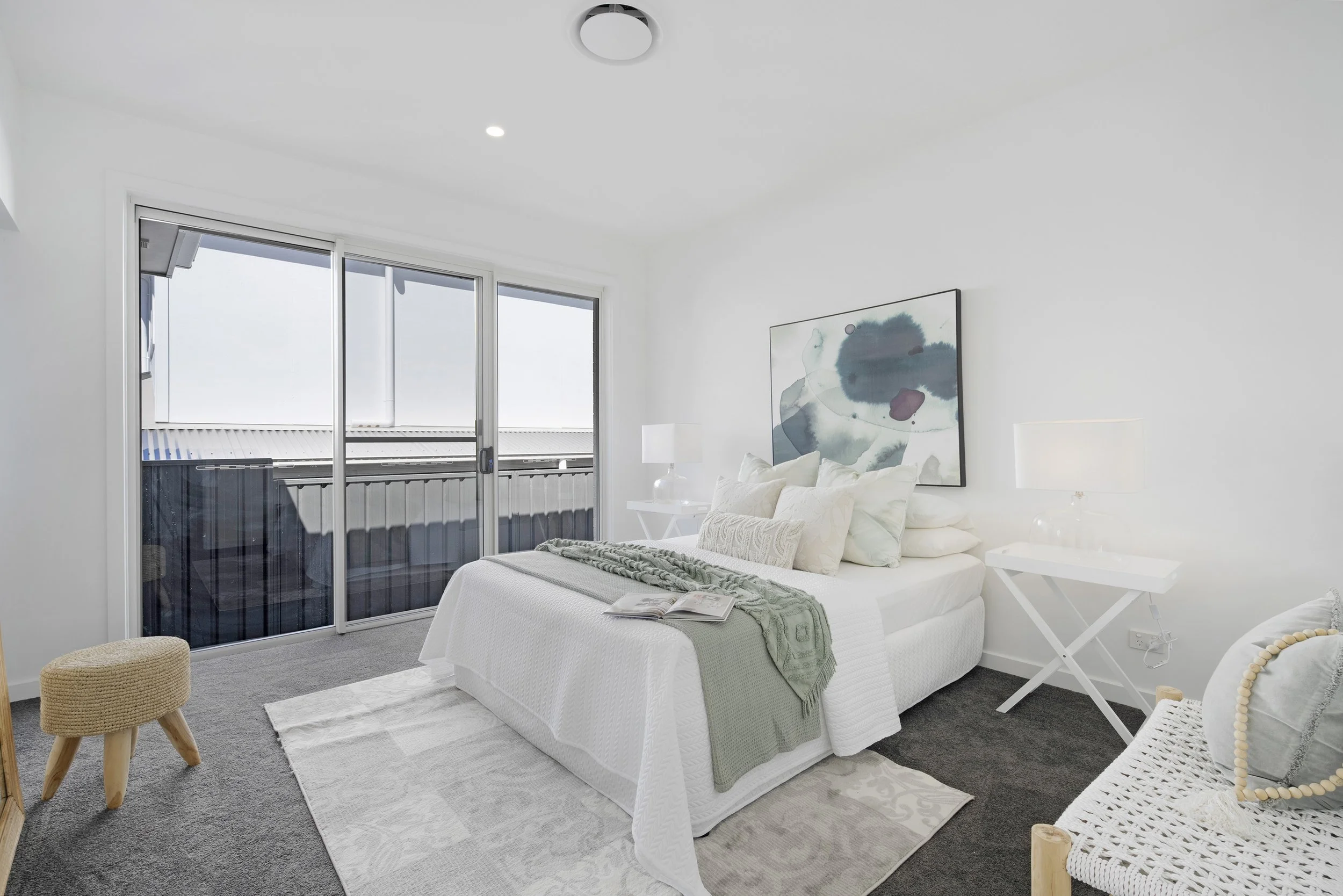 Custom bedroom built with white walls, large sliding glass doors leading to a balcony