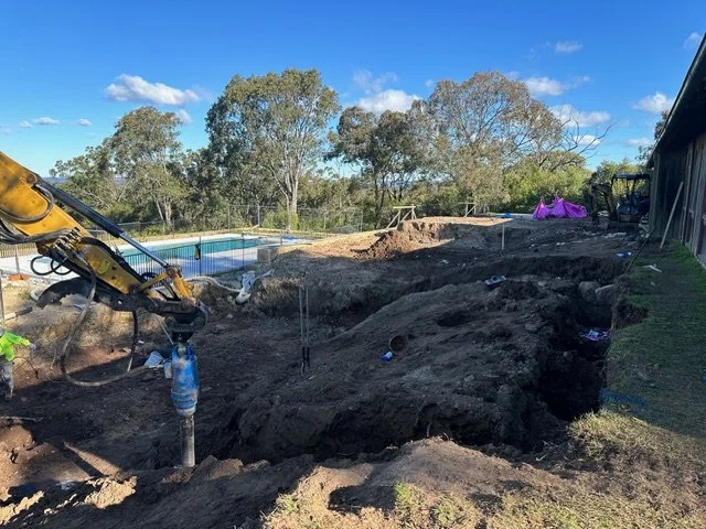 Construction site with excavated dirt and a small excavator
