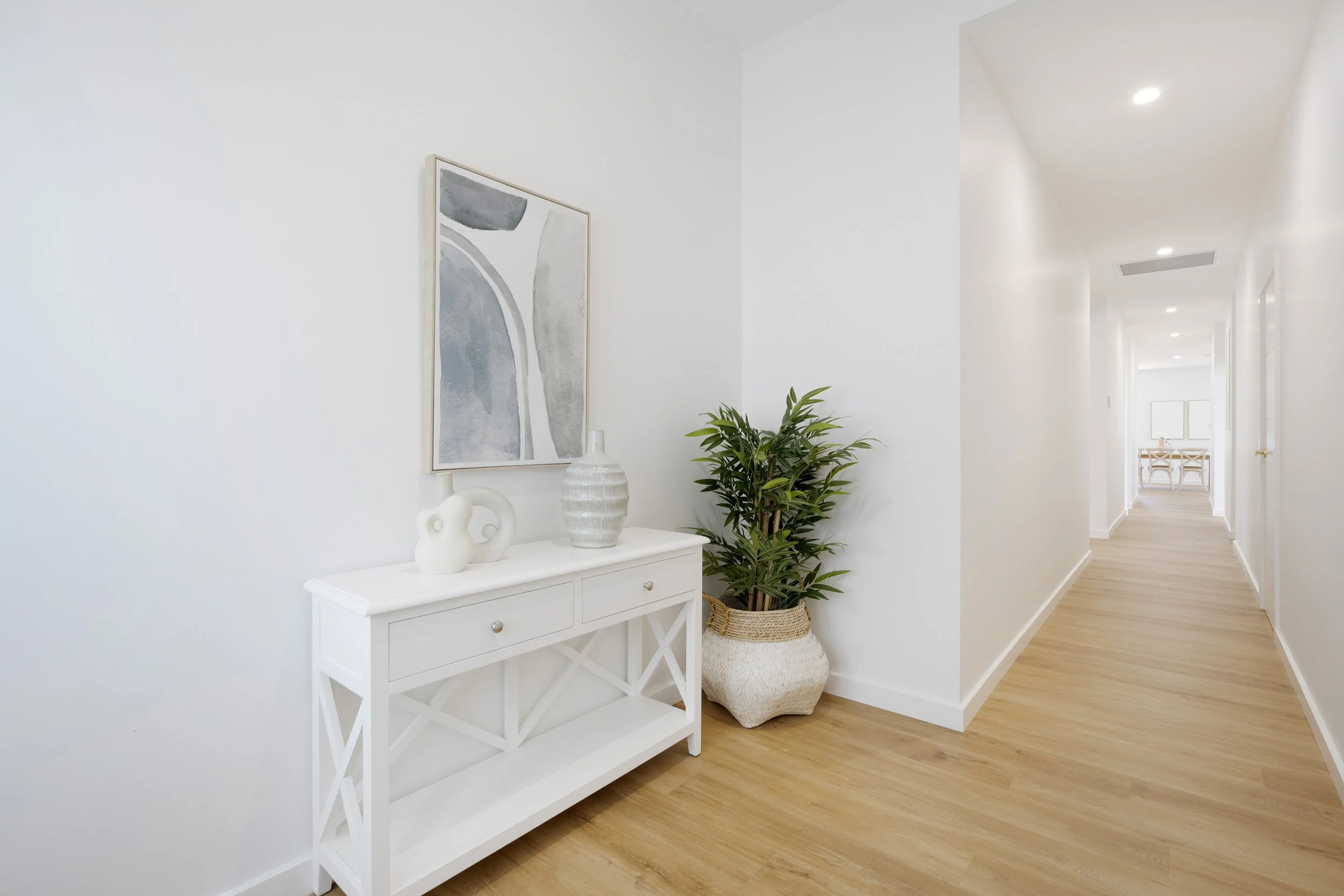 A bright, minimalist hallway with white walls and light wood flooring