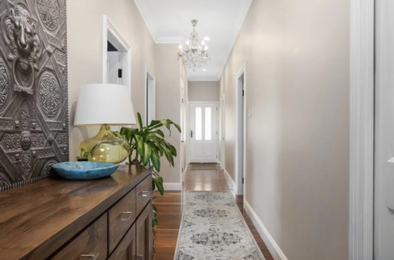 A hallway with wooden flooring, beige walls, a white front door with glass panels