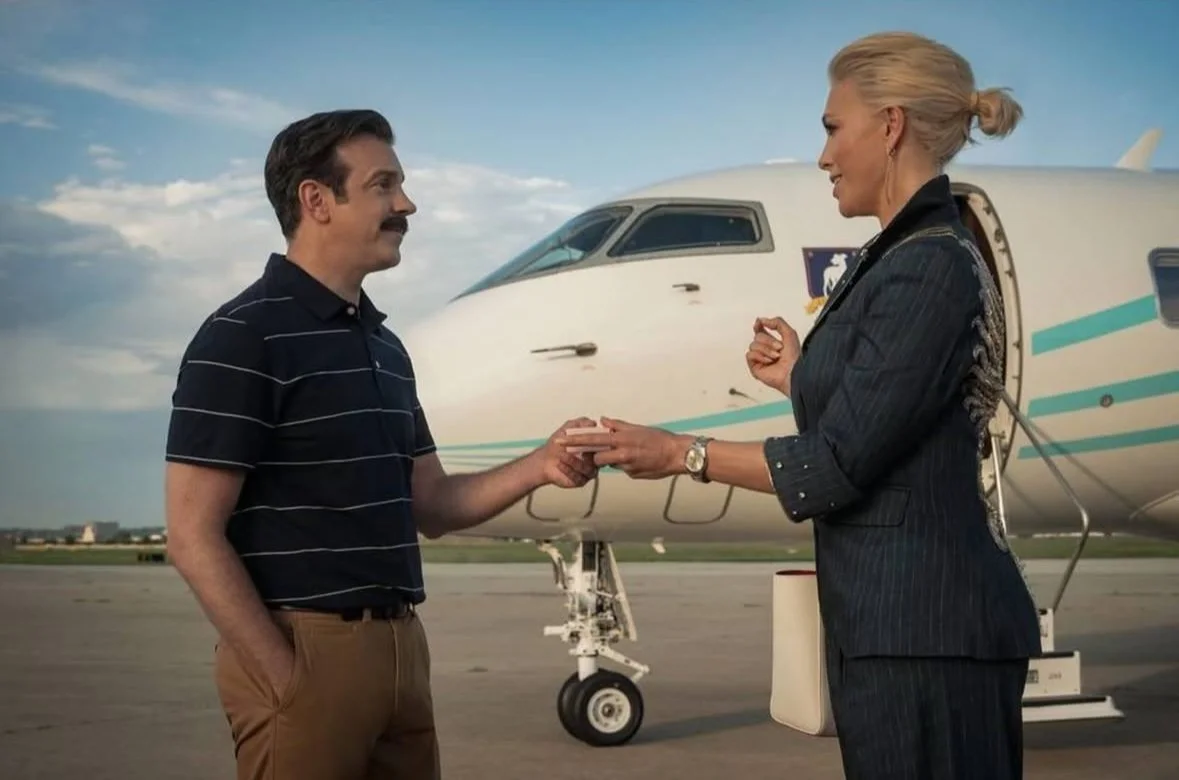 A man and woman exchanging rings in front of a private jet at an airport.
