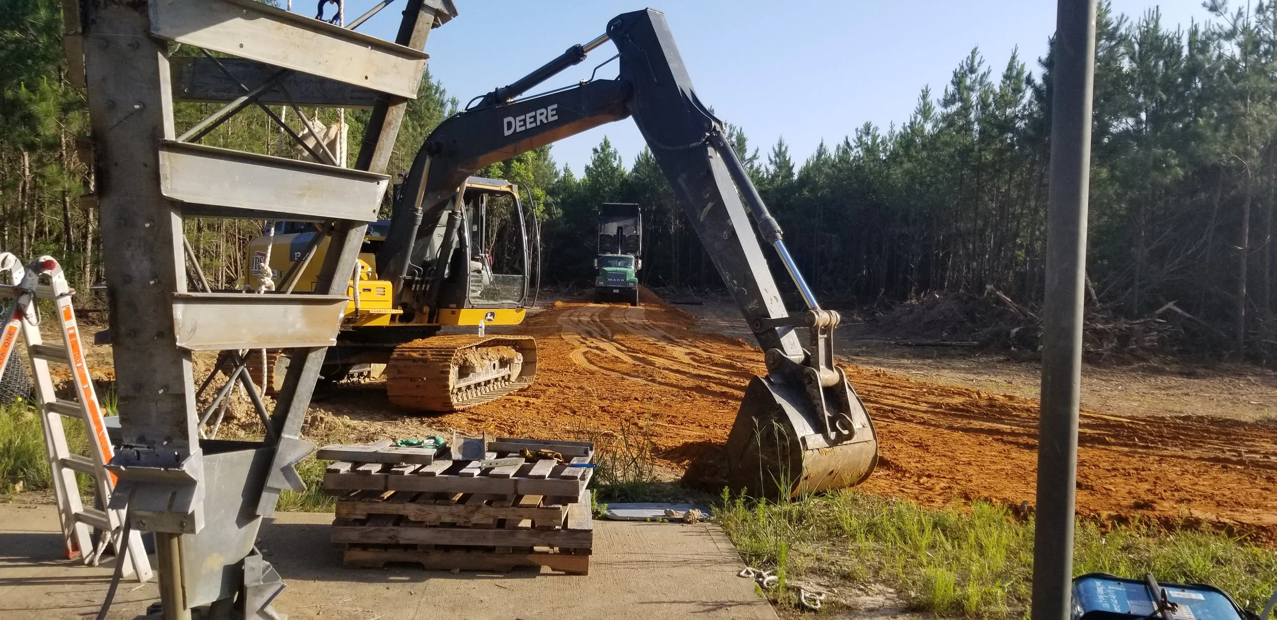 Construction site with an excavator preparing access roads and work areas for communications infrastructure. Site preparation and civil support services for tower construction projects by Green Country Tower Service.