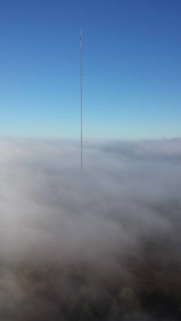 Massive broadcast tower extending above the cloud layer and supporting critical communications infrastructure. High-elevation structural work, tower rigging, inspections, and maintenance services performed nationwide by Green Country Tower Service.