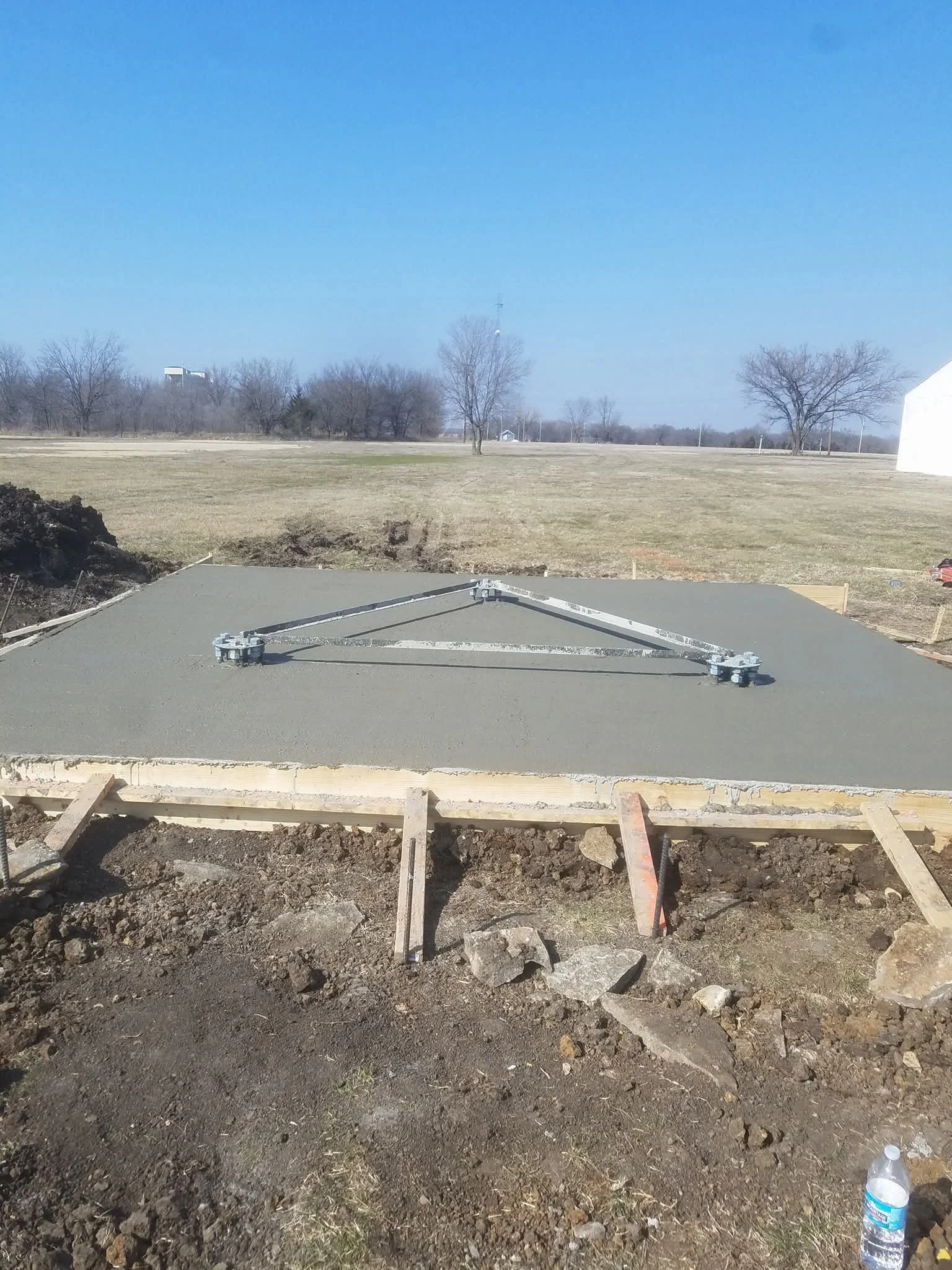 Freshly poured concrete pad and anchor template layout for a new communications tower foundation. Site development, foundation construction, and structural support infrastructure completed by Green Country Tower Service.
