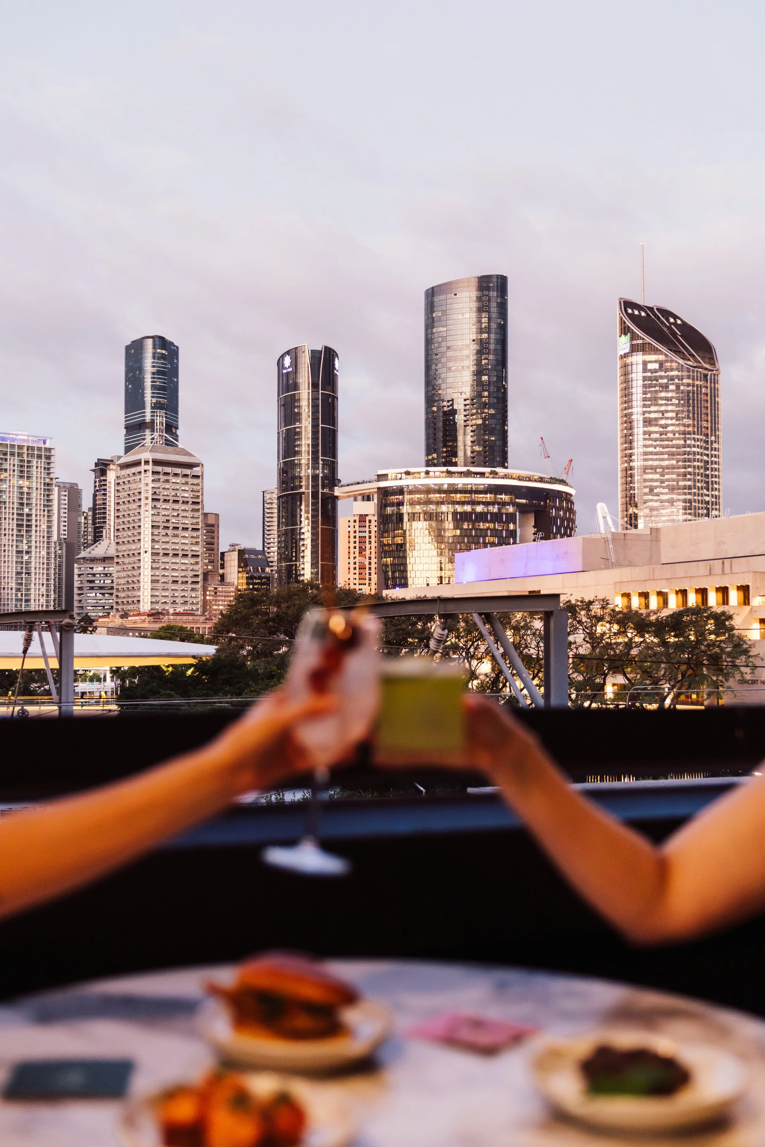 Nighttime rooftop bar with seating area, bar counter with bottles, plants, and city skyline view, logo of a fox and the text 'FOX ROOFTOP'. 