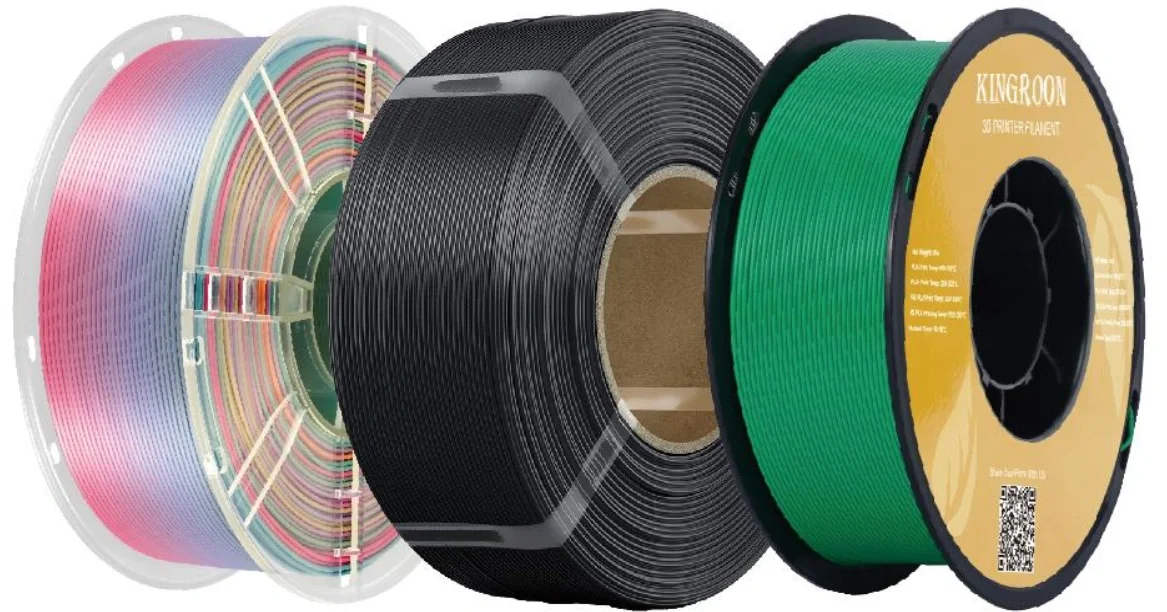 Three spools of 3D printer filament in pastel pink, black, and green colors.