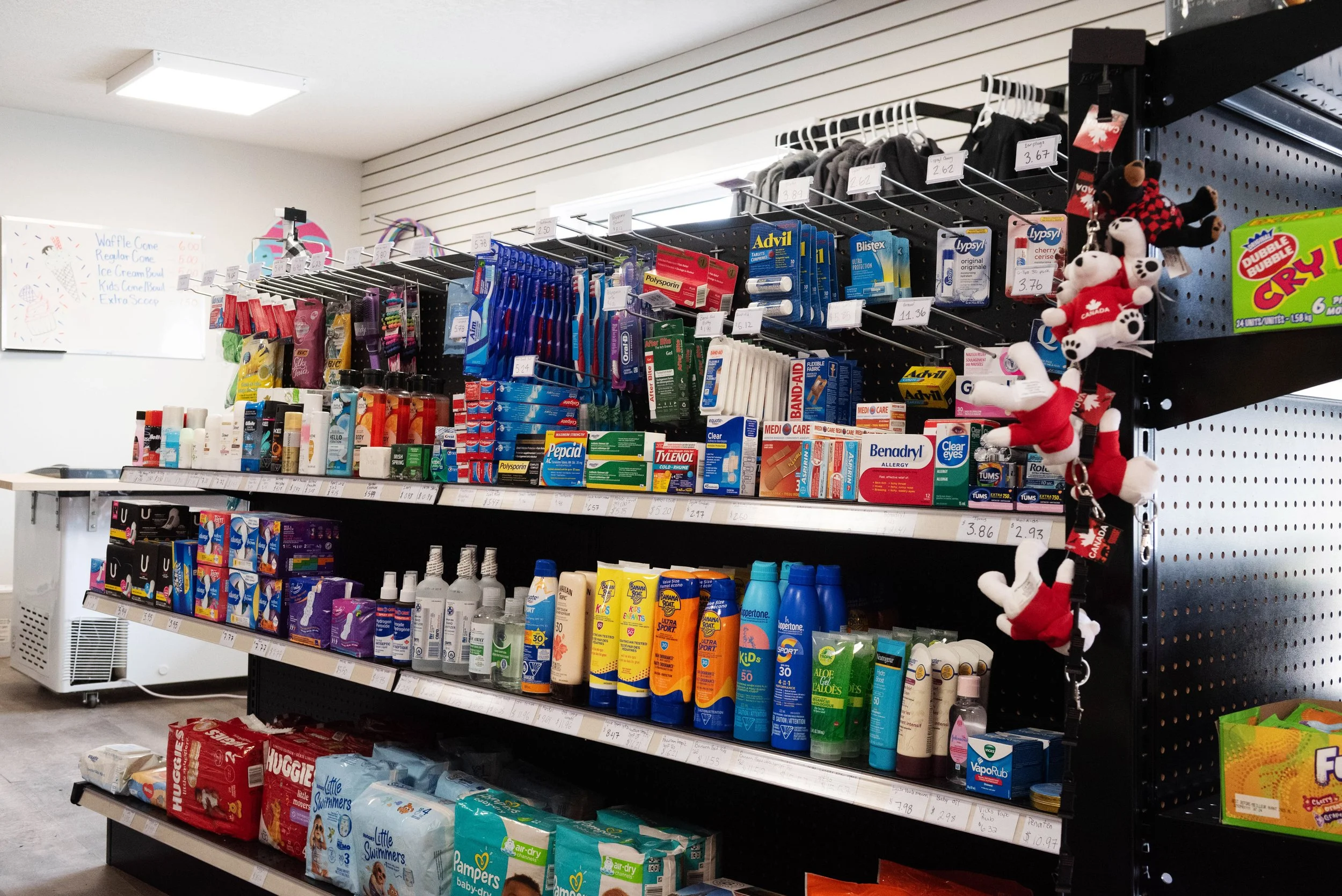 Store aisle with shelves of health and personal care products including sunscreen, baby wipes, bug spray, and other skincare items.