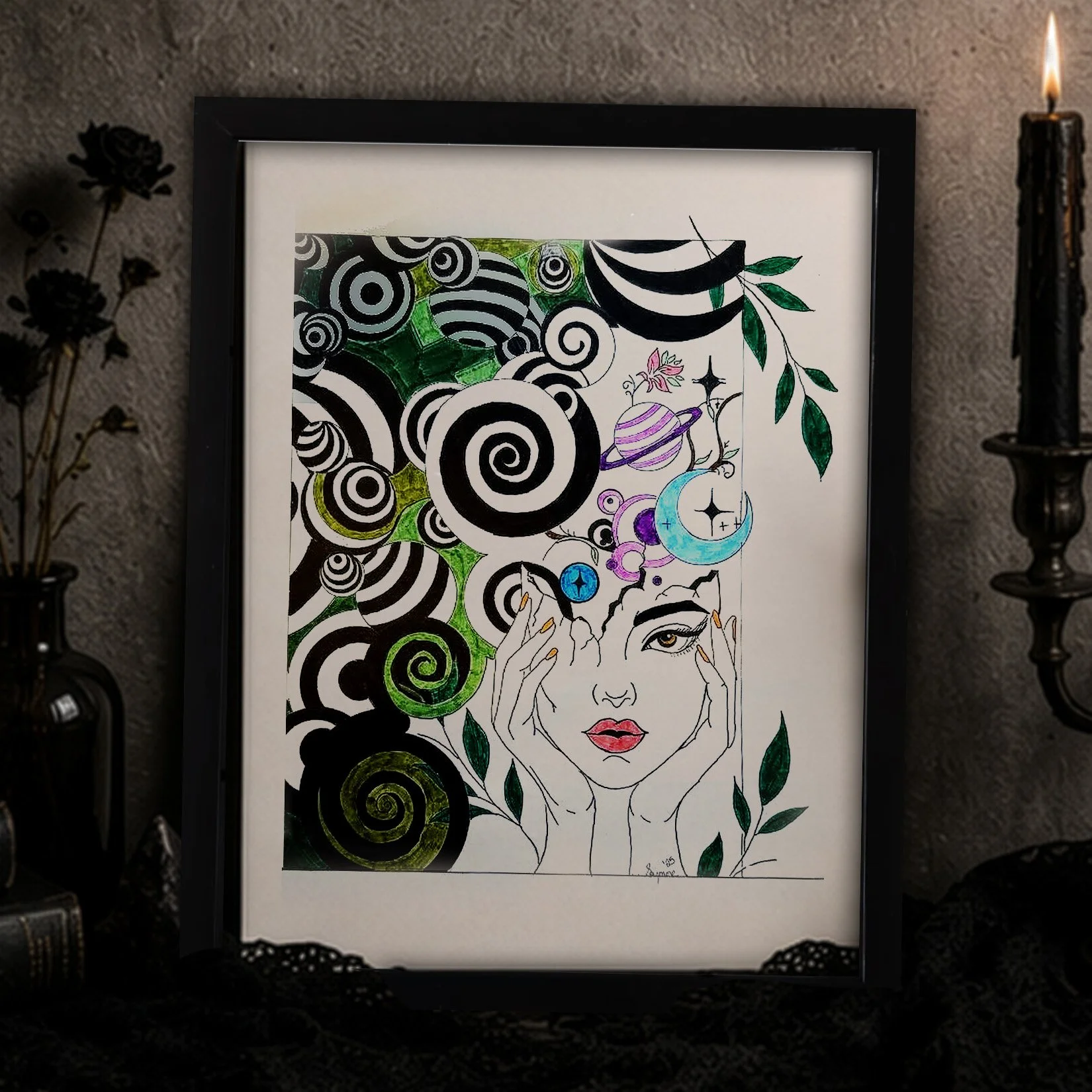 Framed illustration of a woman with long hair, holding her face with both hands, surrounded by colorful cosmic and spiral patterns and green leaves, set against a dark background with black candlestick holders and dried flowers.