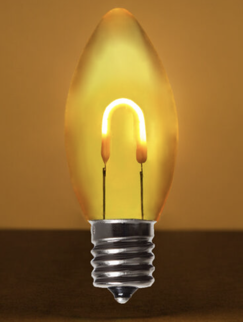 A close-up of a lightbulb with a filament shaped like a horseshoe, emitting a warm yellow glow, against a yellow background.