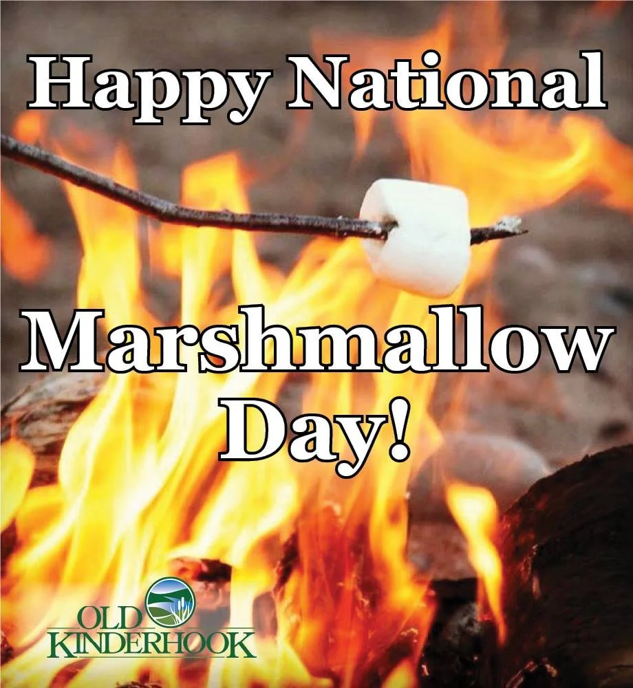 Marshmallow on a stick being roasted over an open flame, with text that reads 'Happy National Marshmallow Day!' and a small logo at the bottom left that says 'Old Kinderhook.'