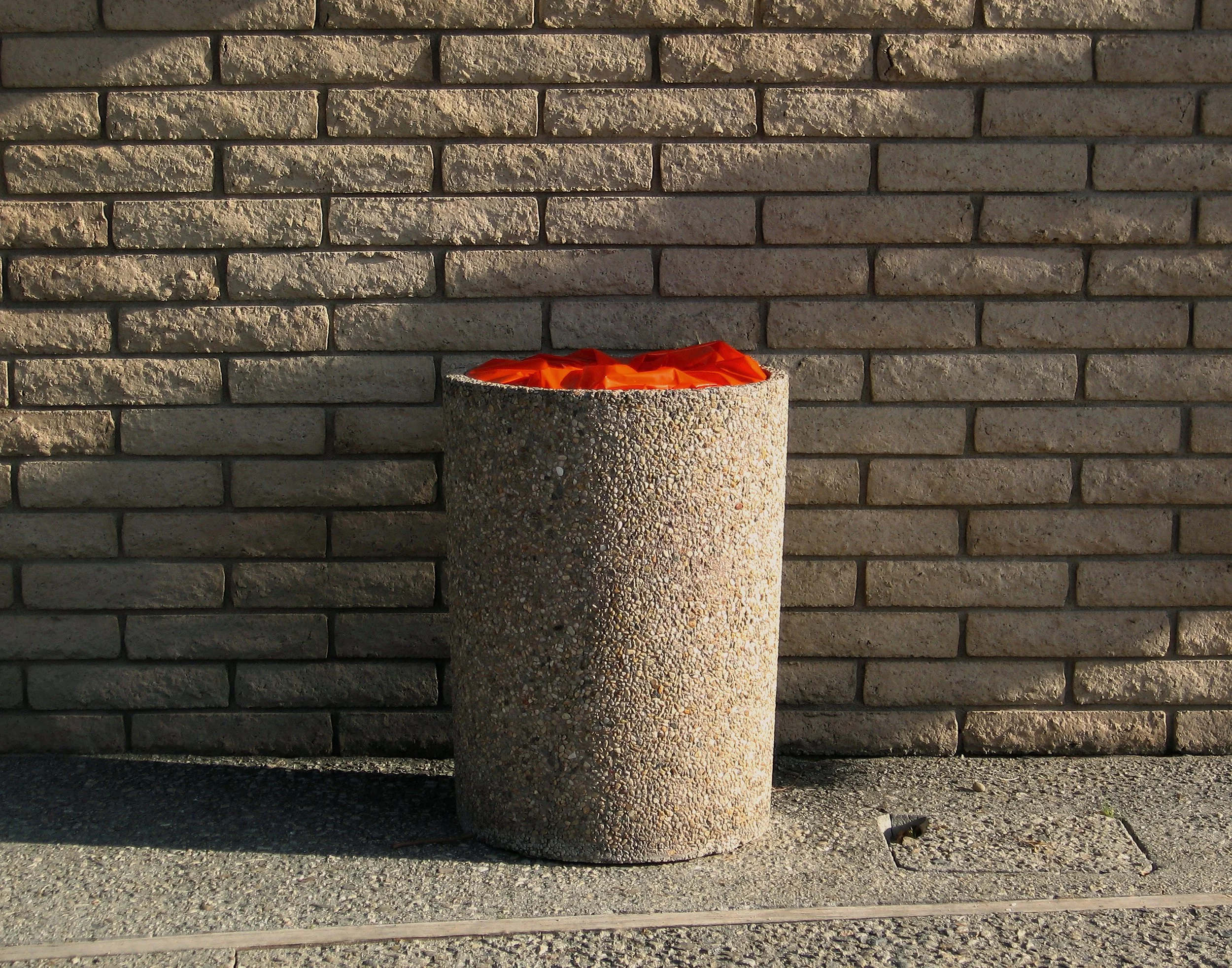 Beige trash can, brick wall, orange top