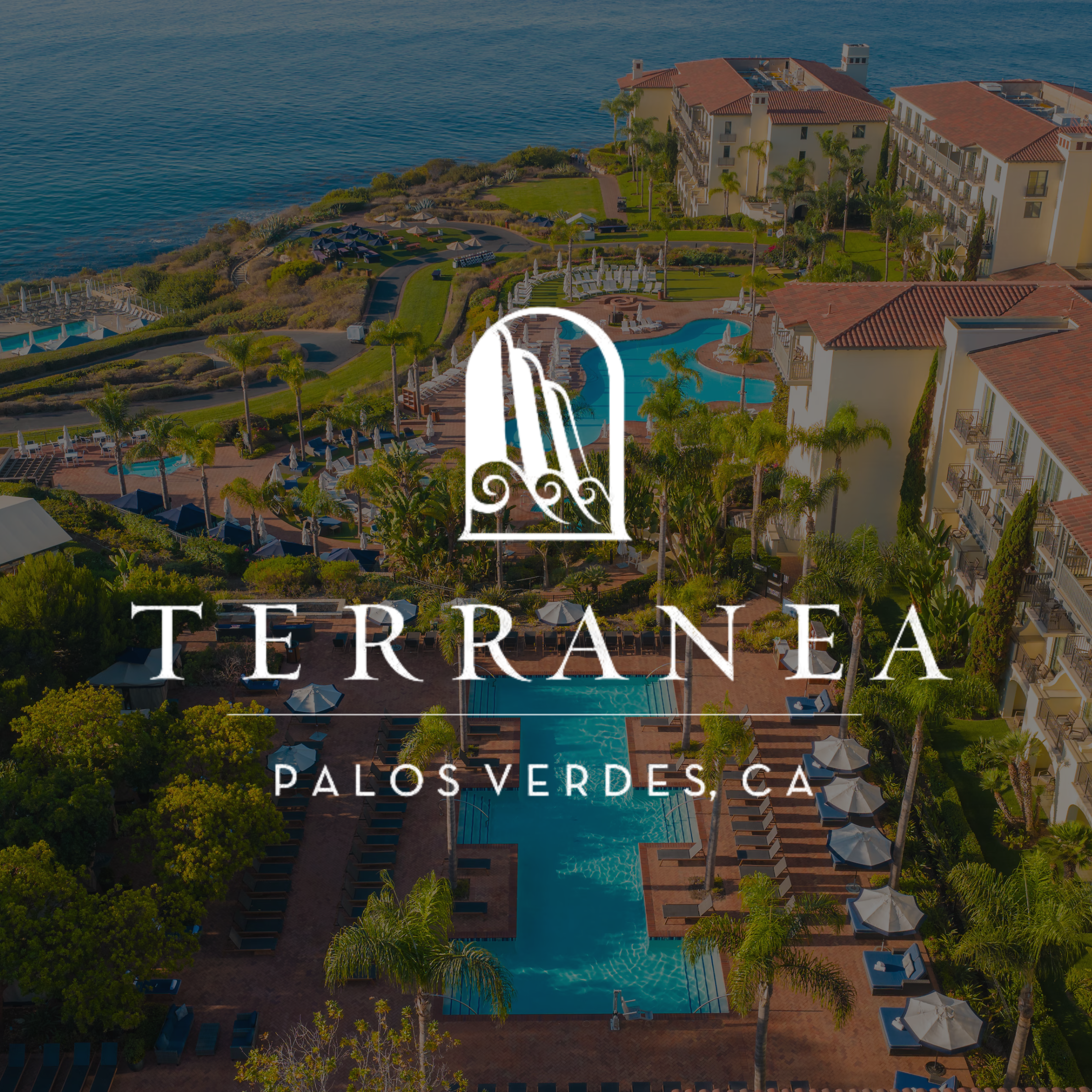Aerial view of a luxury apartment complex with swimming pools, palm trees, and a view of the ocean, promoting Terrawind Palos Verdes, CA.