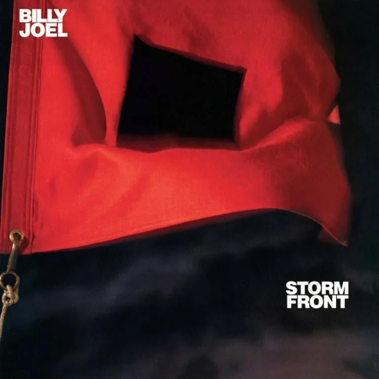 Close-up of a red jacket with a black pocket and white text labels saying 'Billy Joel' in the top left corner and 'Storm Front' in the bottom right corner.
