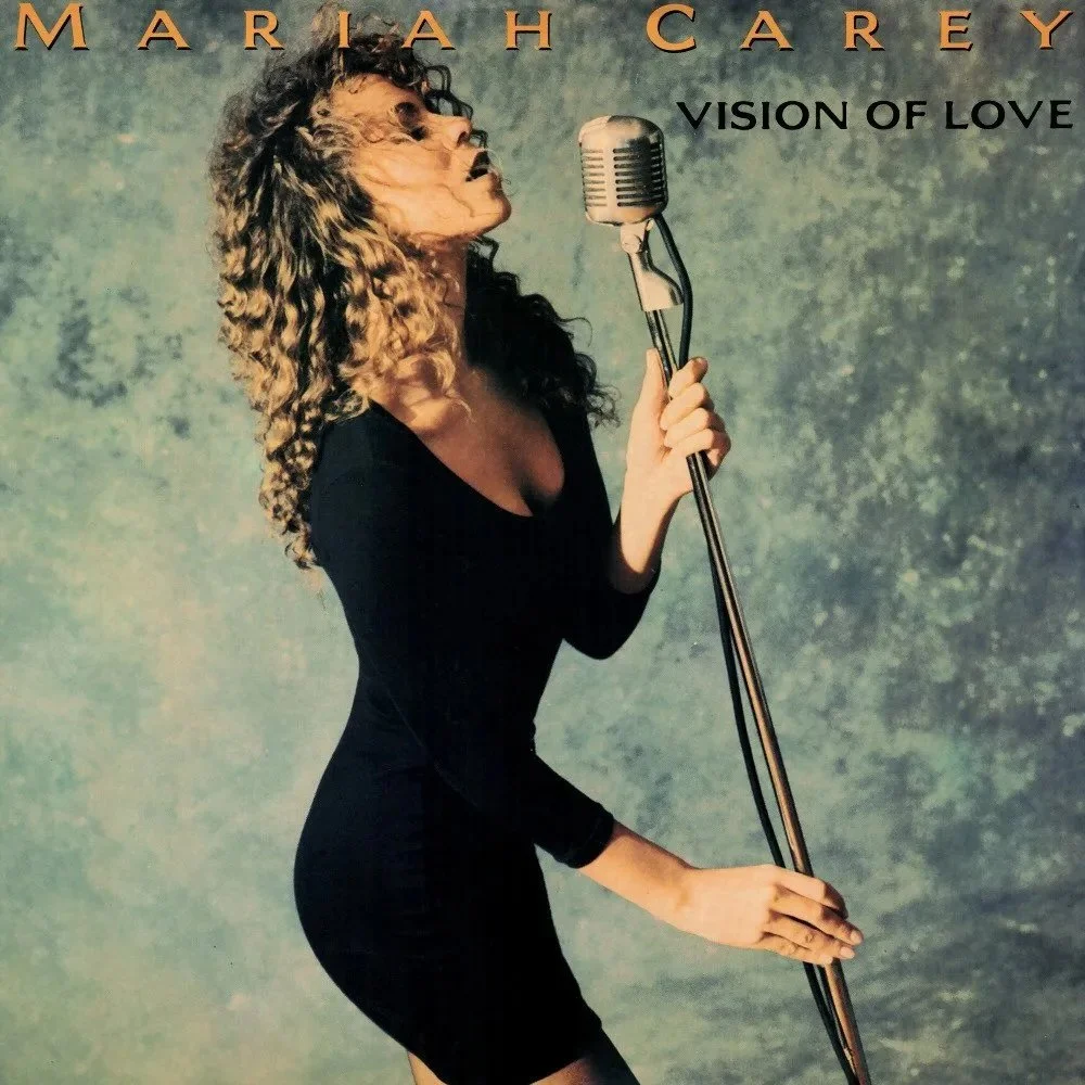 Music album cover featuring a woman with a lion's face singing into a vintage microphone, holding the microphone stand, with text indicating 'MARIAN CAREY' and 'VISION OF LOVE'.