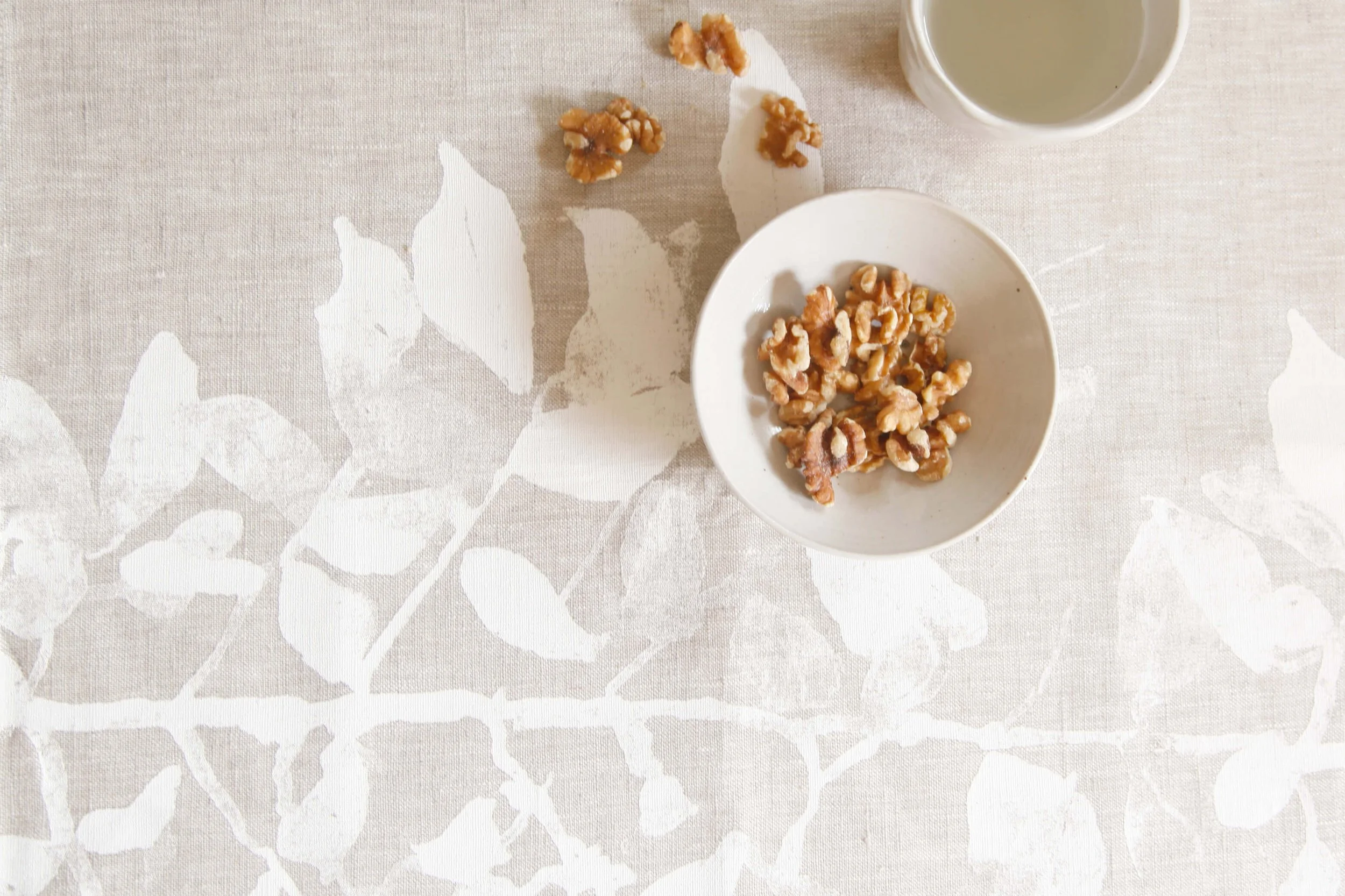 Nature-inspired linen homewares collection featuring hand screen printed botanical surface designs on tea towels and cushions.