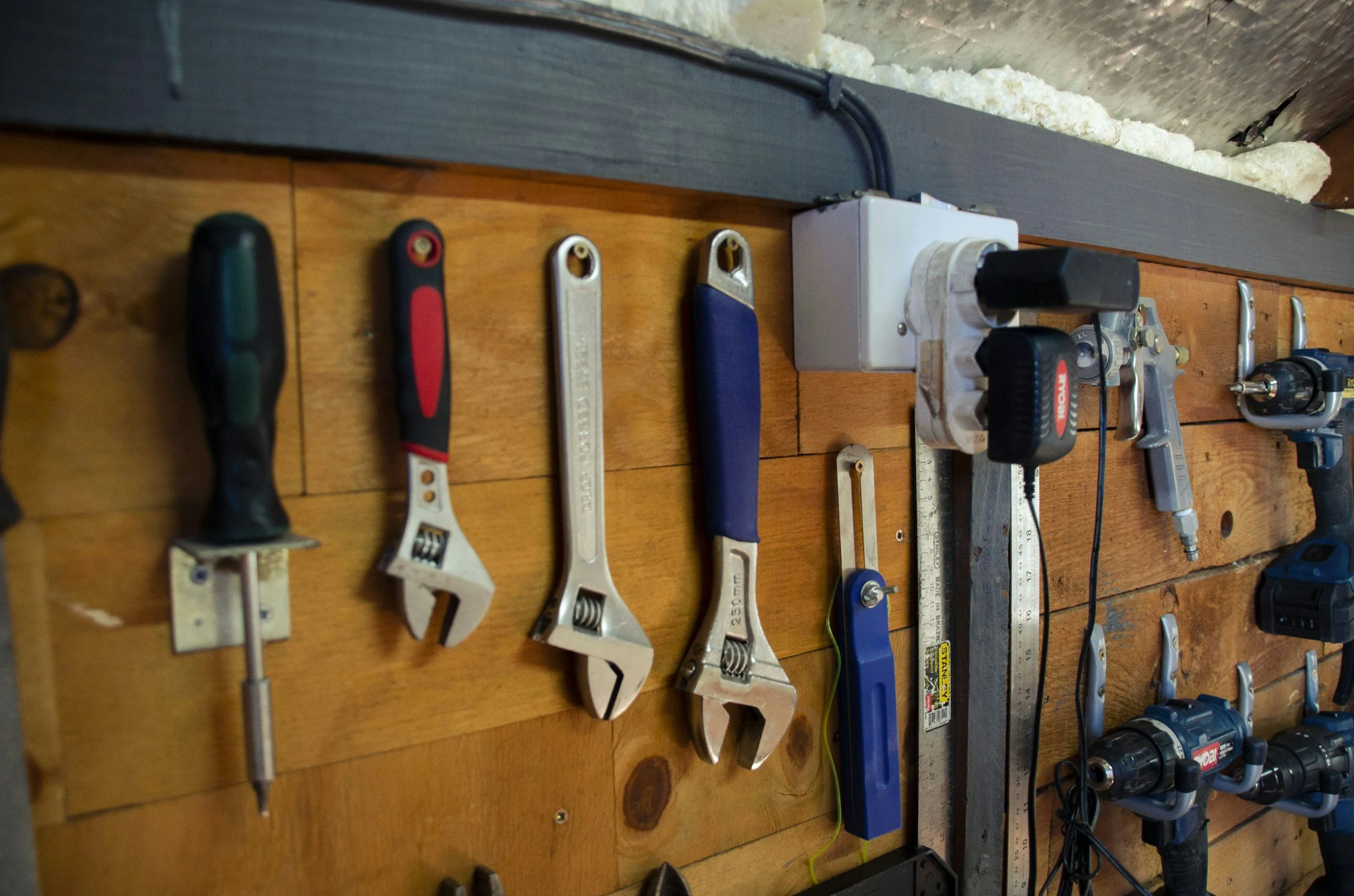 Various hand tools and power tools laid out on a wooden workbench, including screwdrivers, wrenches, a saw, a level, and a drill.