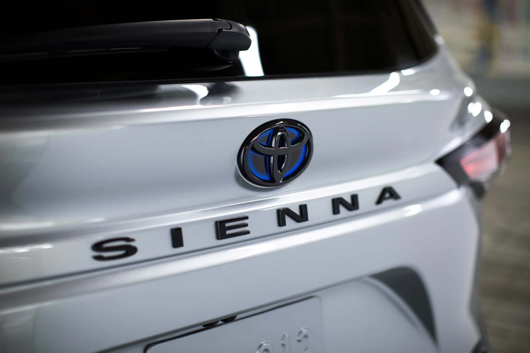 Close-up of the rear of a white Toyota Sienna minivan, showing the Toyota emblem and the model name on the back.