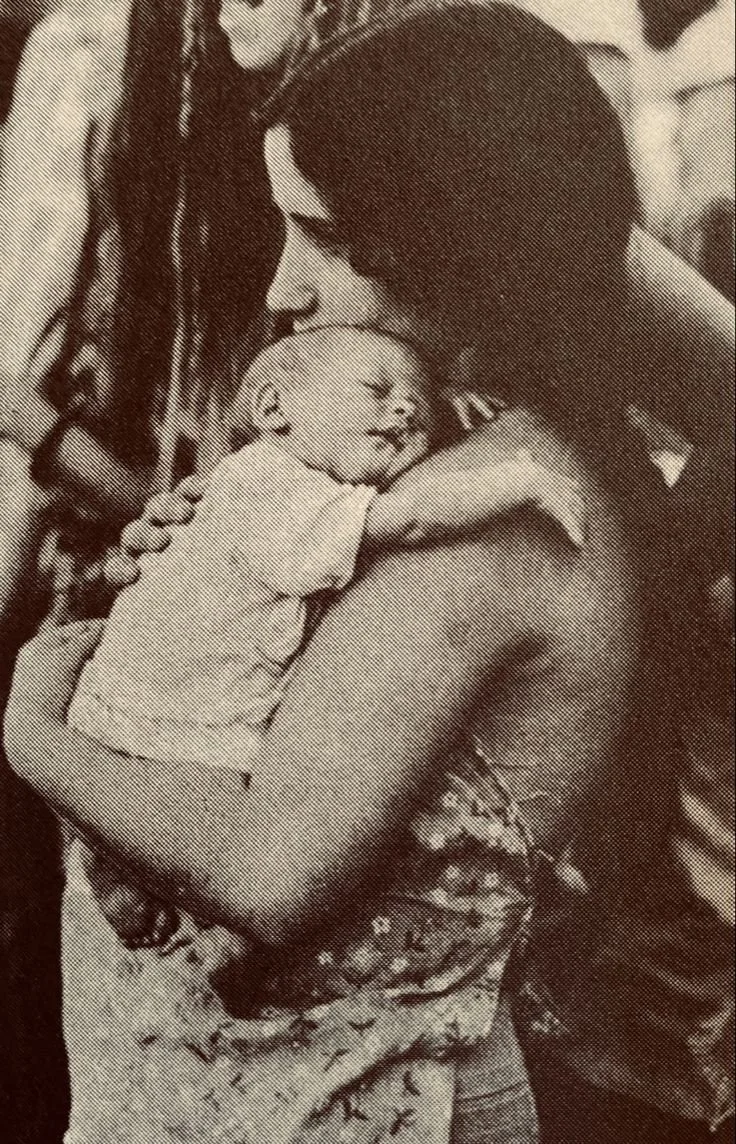 A young boy is hugging an adult woman, possibly his mother, with eyes closed and a smile. The woman is holding the boy in an embrace, and they appear to be sharing an intimate, happy moment.