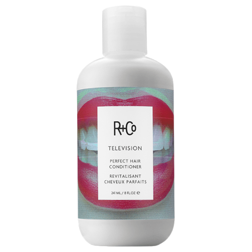 A white bottle of R+Co Television Perfect Hair Conditioner with a label showing a red lips graphic and text in black and white.