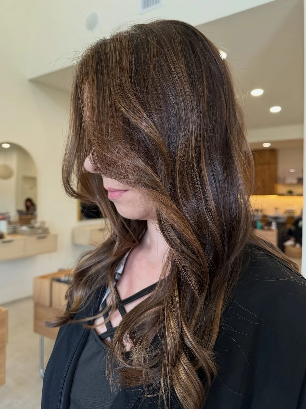 Rich dimensional brunette balayage with warm caramel ribbons and a brighter money piece around the face.