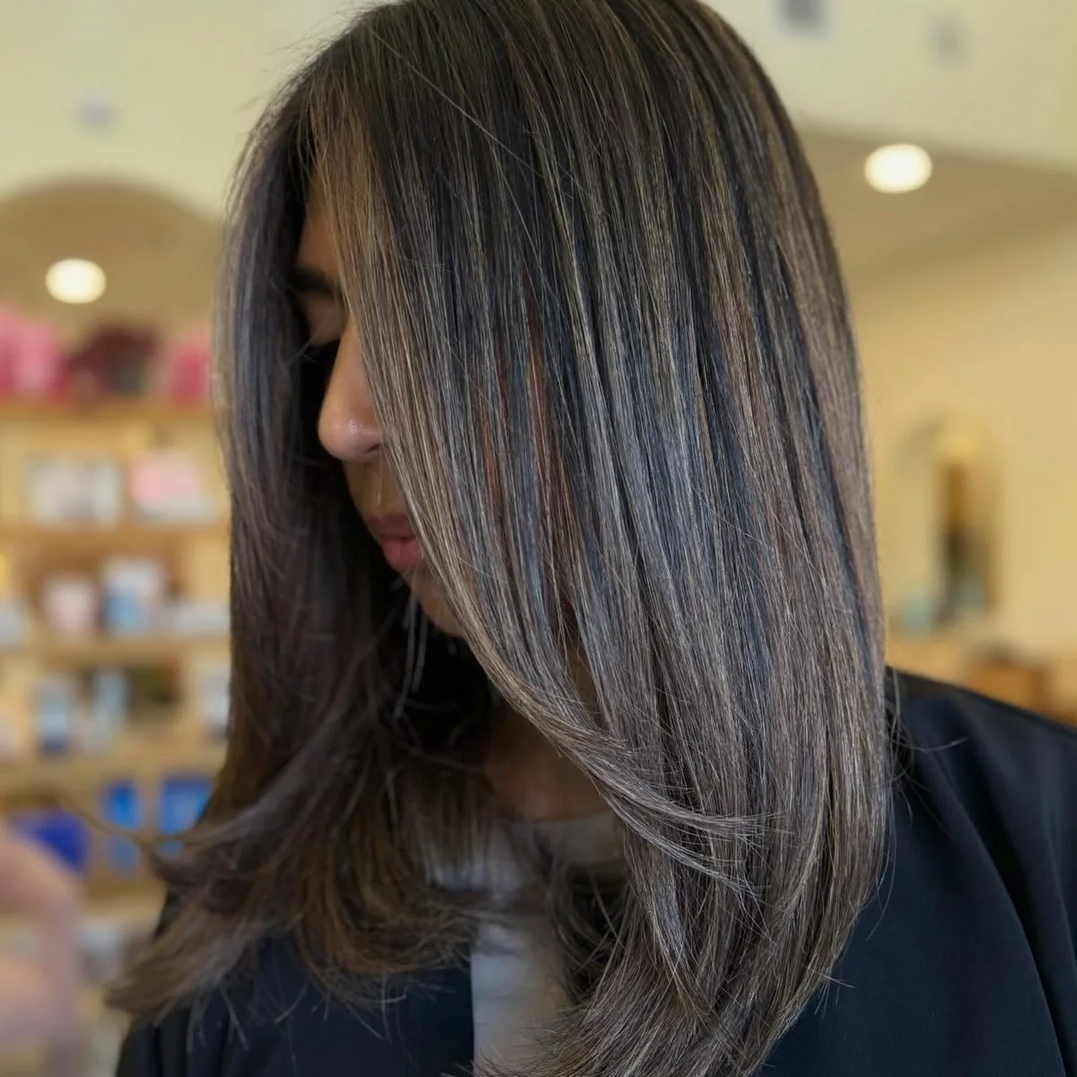 Glossy cool-toned dimensional brunette with soft ash ribbons, styled sleek at Lotus Boutique Salon in Tomball, TX.
