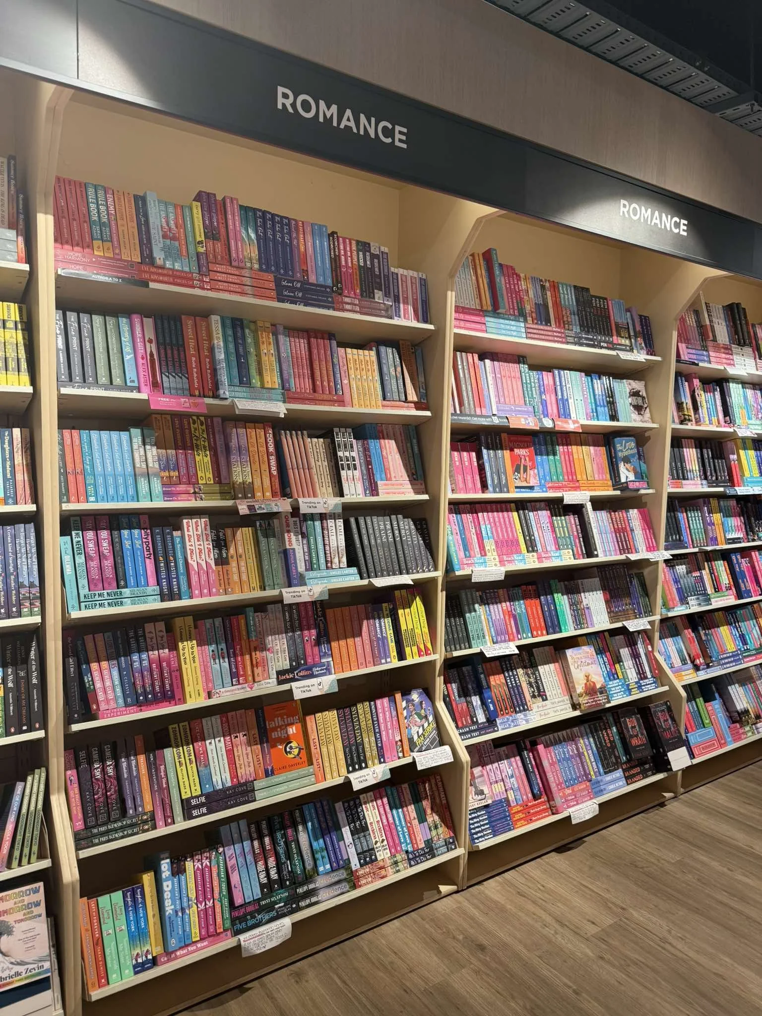 Bookshelves labeled 'Romance' filled with romance novels in a bookstore