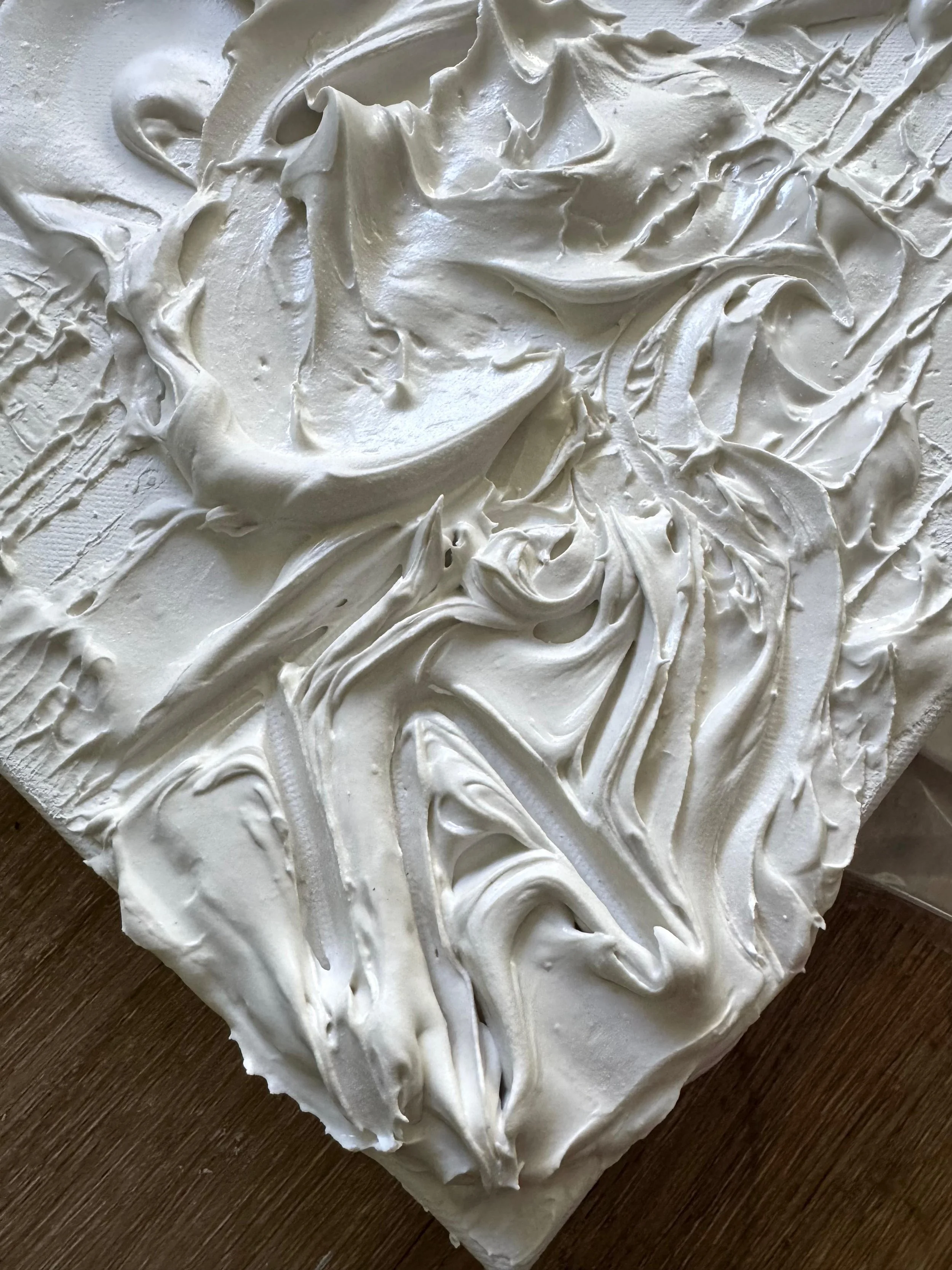 Close-up of a white, textured painting, with the artist signature.
