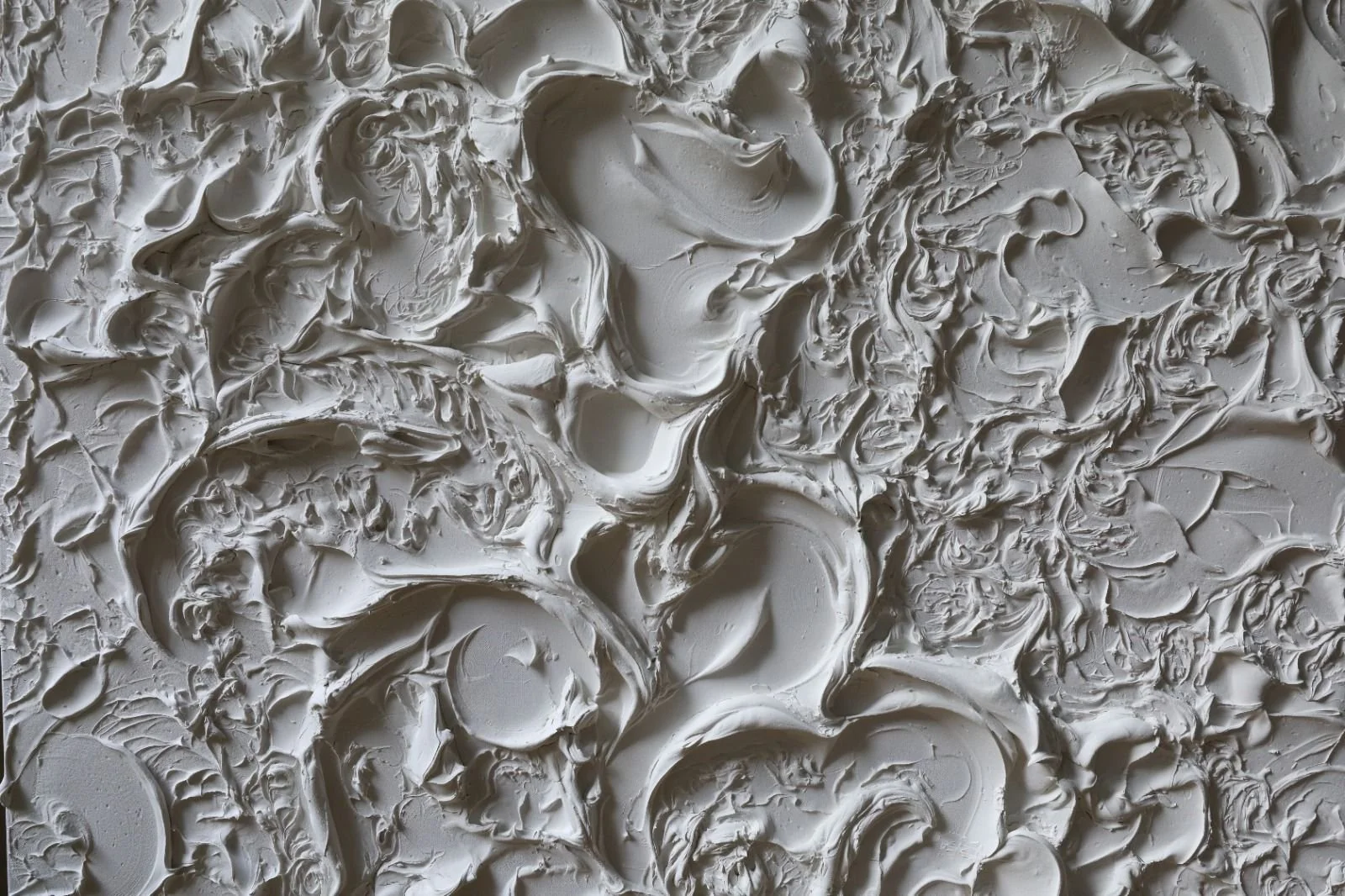 Close-up of a surface with thick, textured, white acrylic with swirling patterns and ridges.
