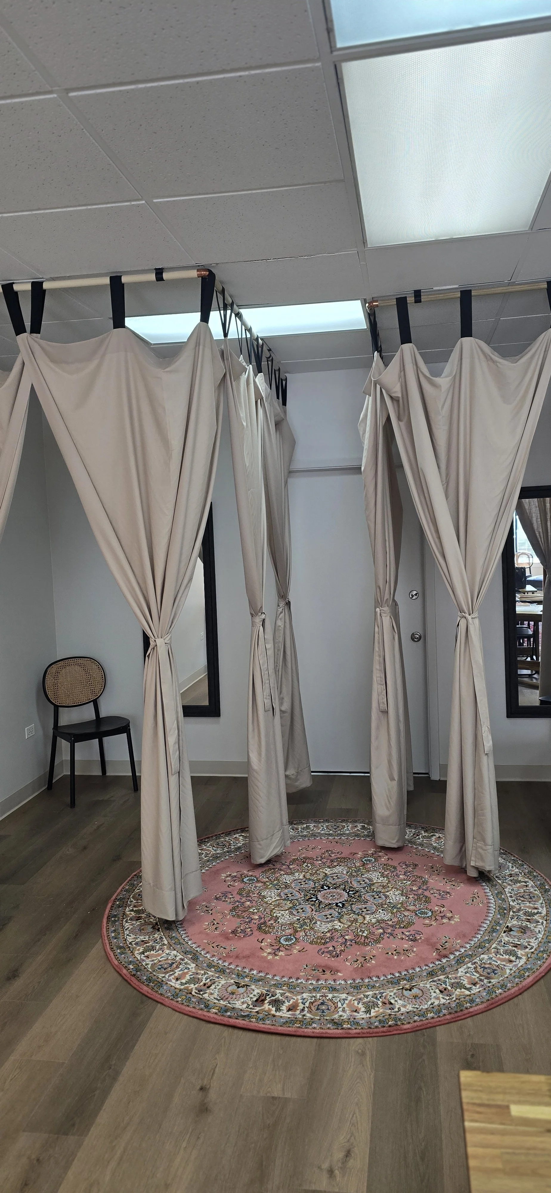 Two fitting rooms with linen curtains and black framed mirrors